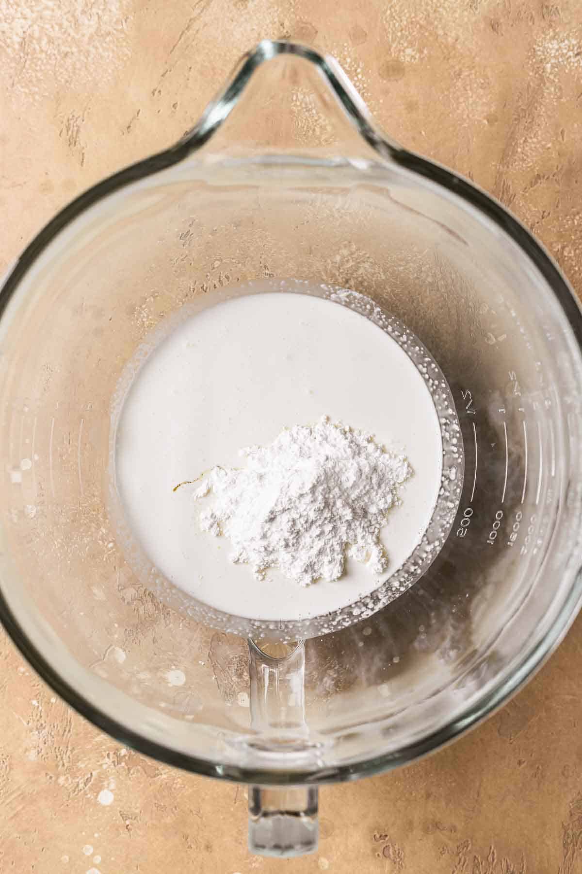 Heavy cream, powdered sugar and vanilla in a glass mixing bowl.