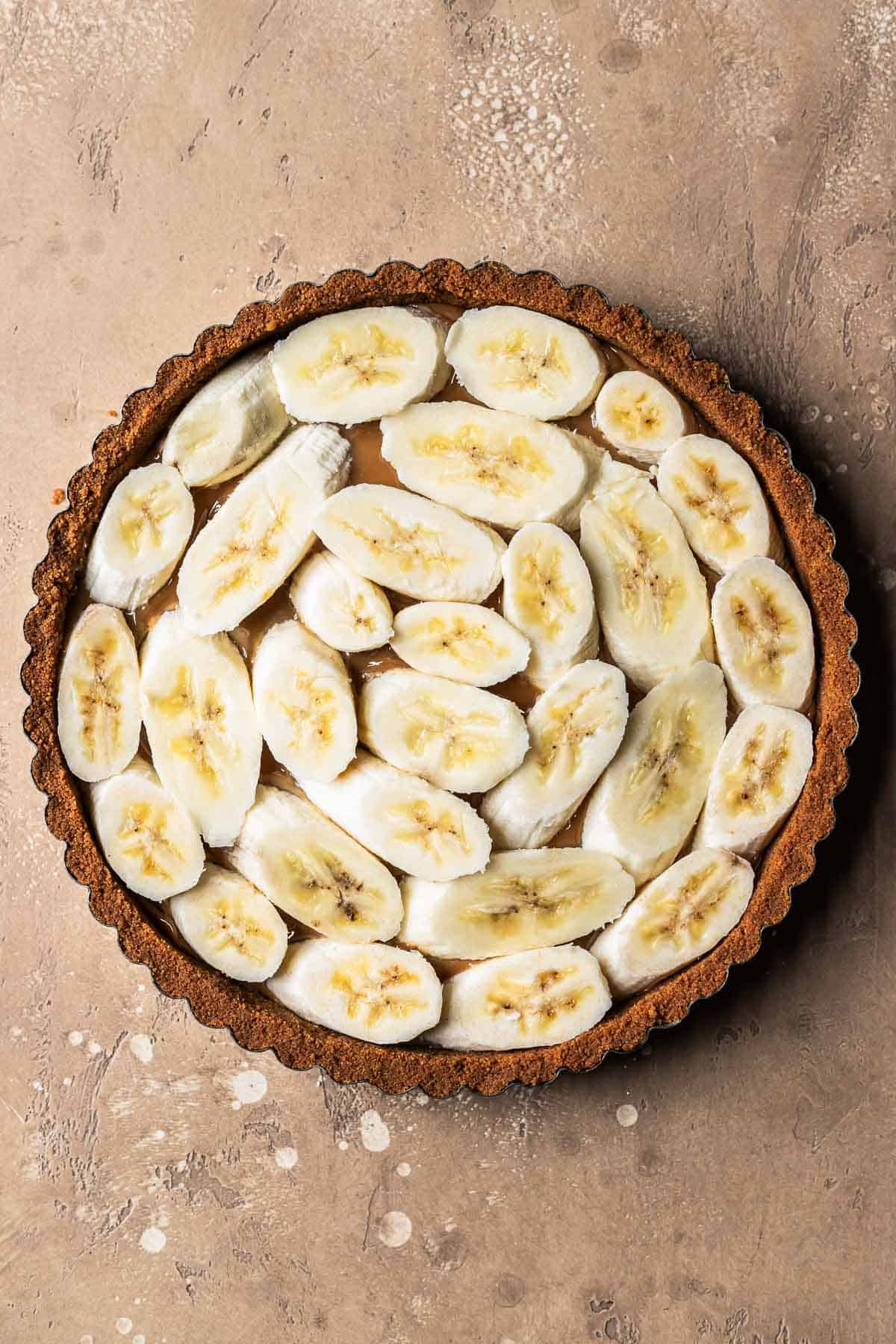 Sliced bananas on top of dulce de leche in a biscoff tart crust.