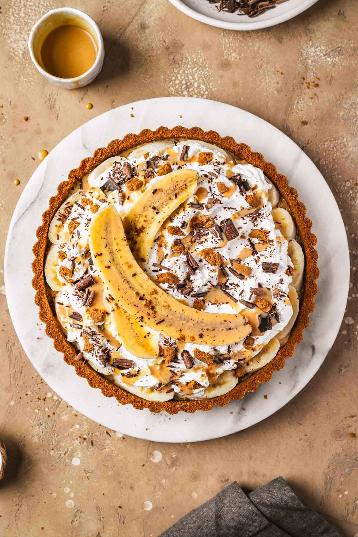 A caramel banana tart on a marble platter.