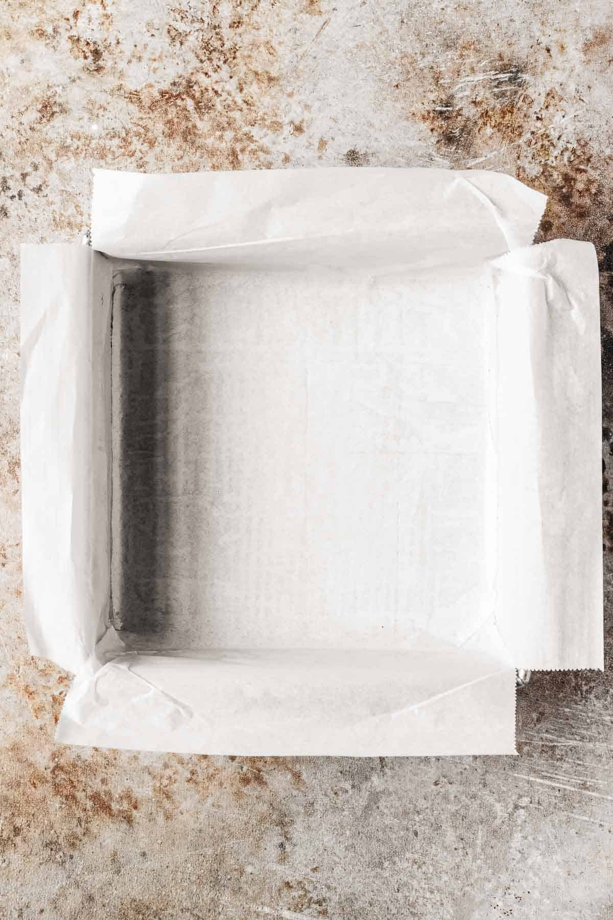 An 8 inch square pan lined with parchment paper.