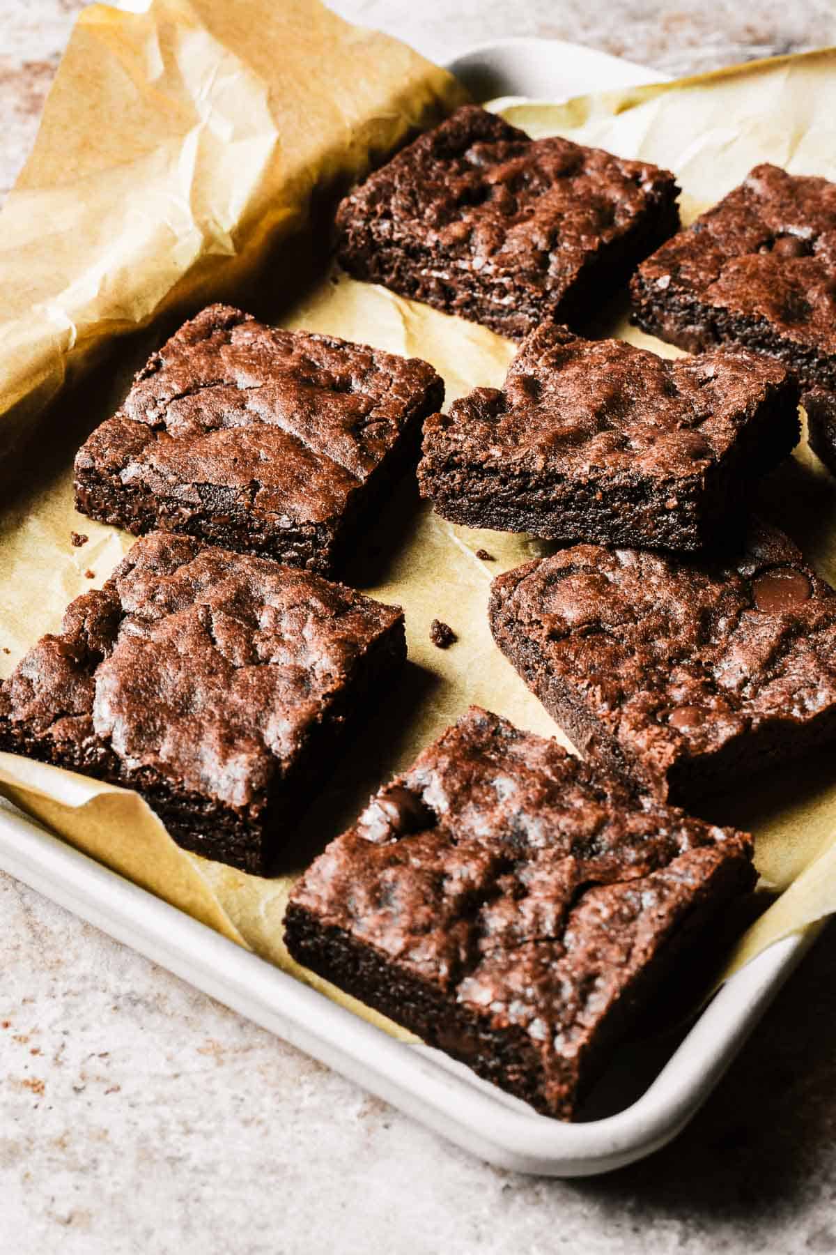 Double chocolate chip cookie bar squares on a parchment paper lined tray.
