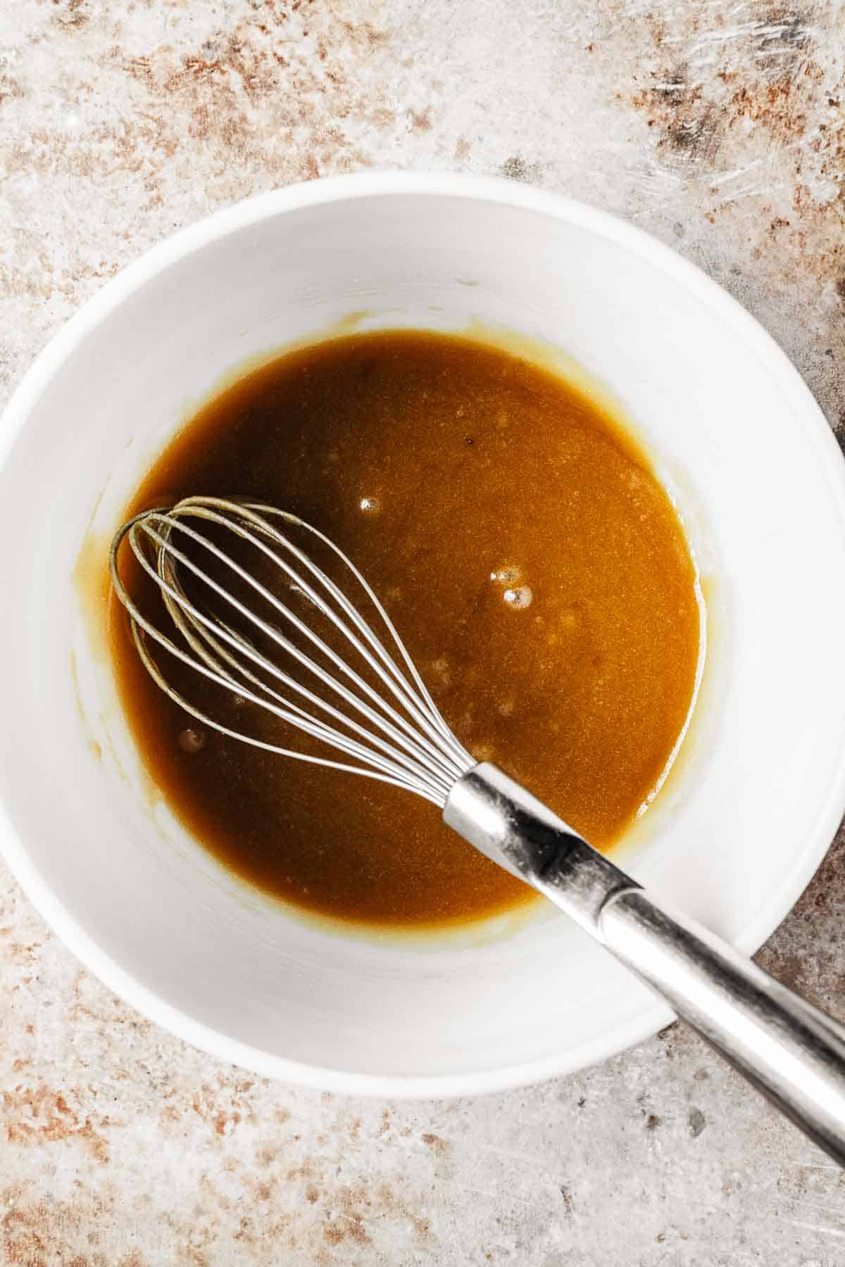 A mixing bowl with oil and sugars combined.