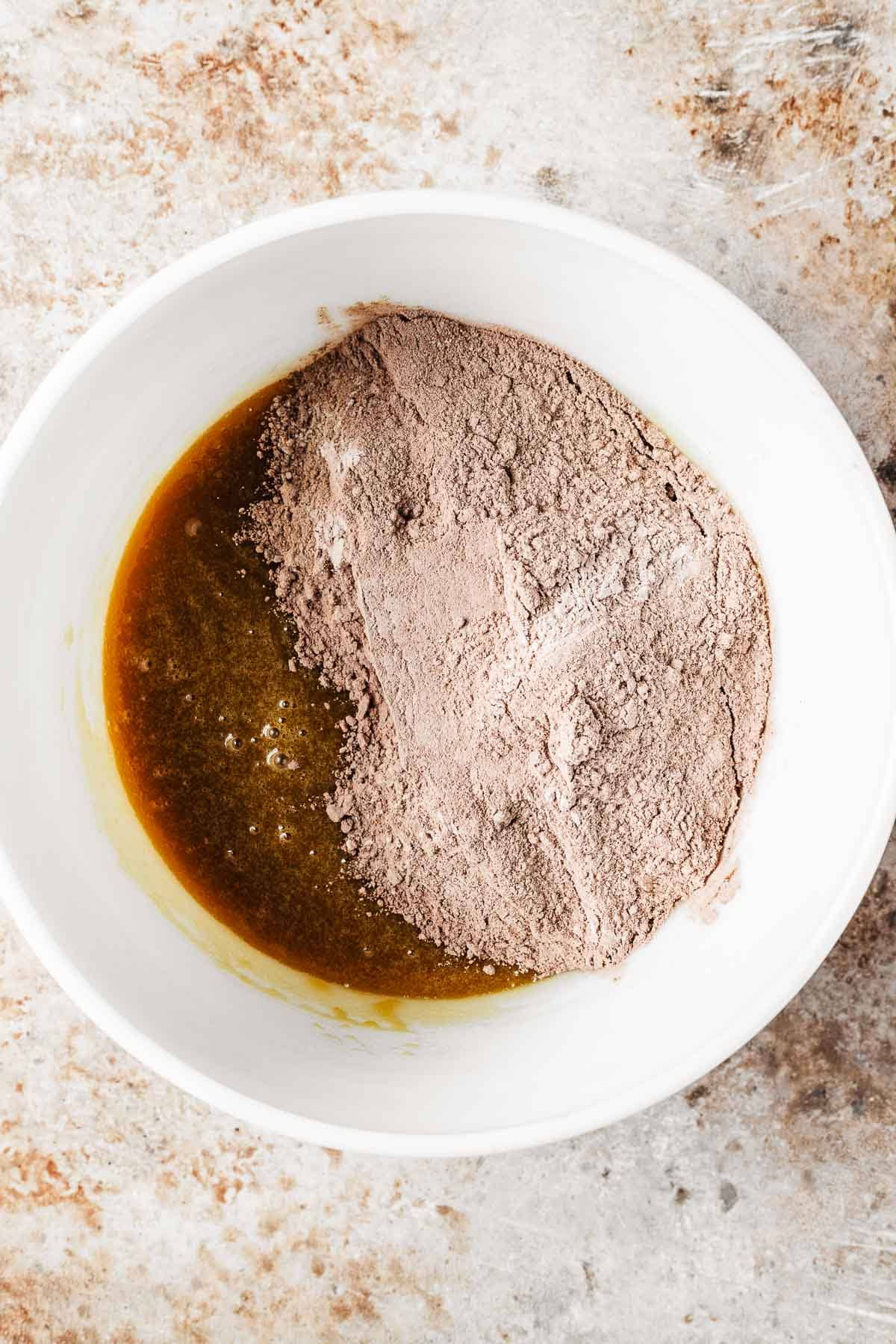Dry ingredients added to wet ingredients in a mixing bowl.