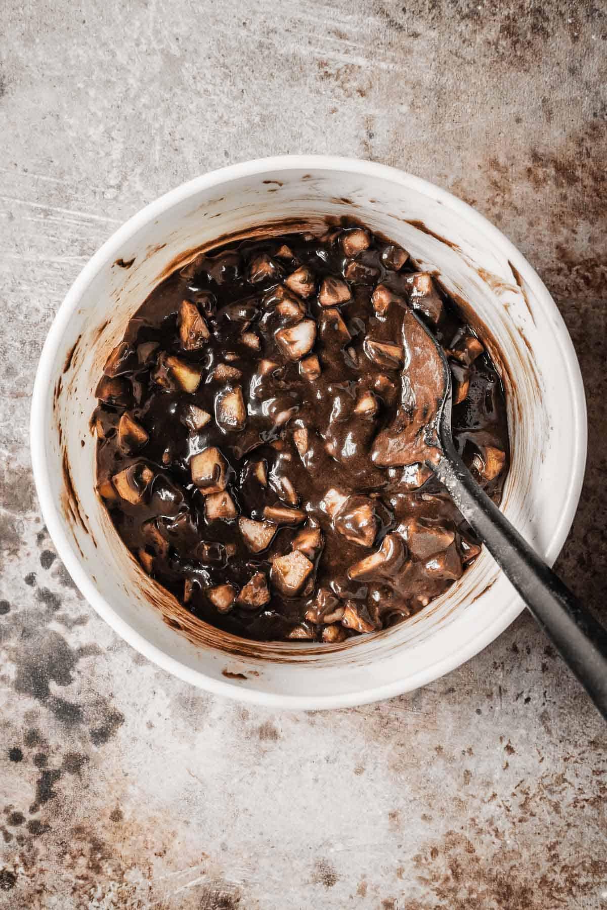 A mixing bowl with diced pears stirred into chocolate cake batter.