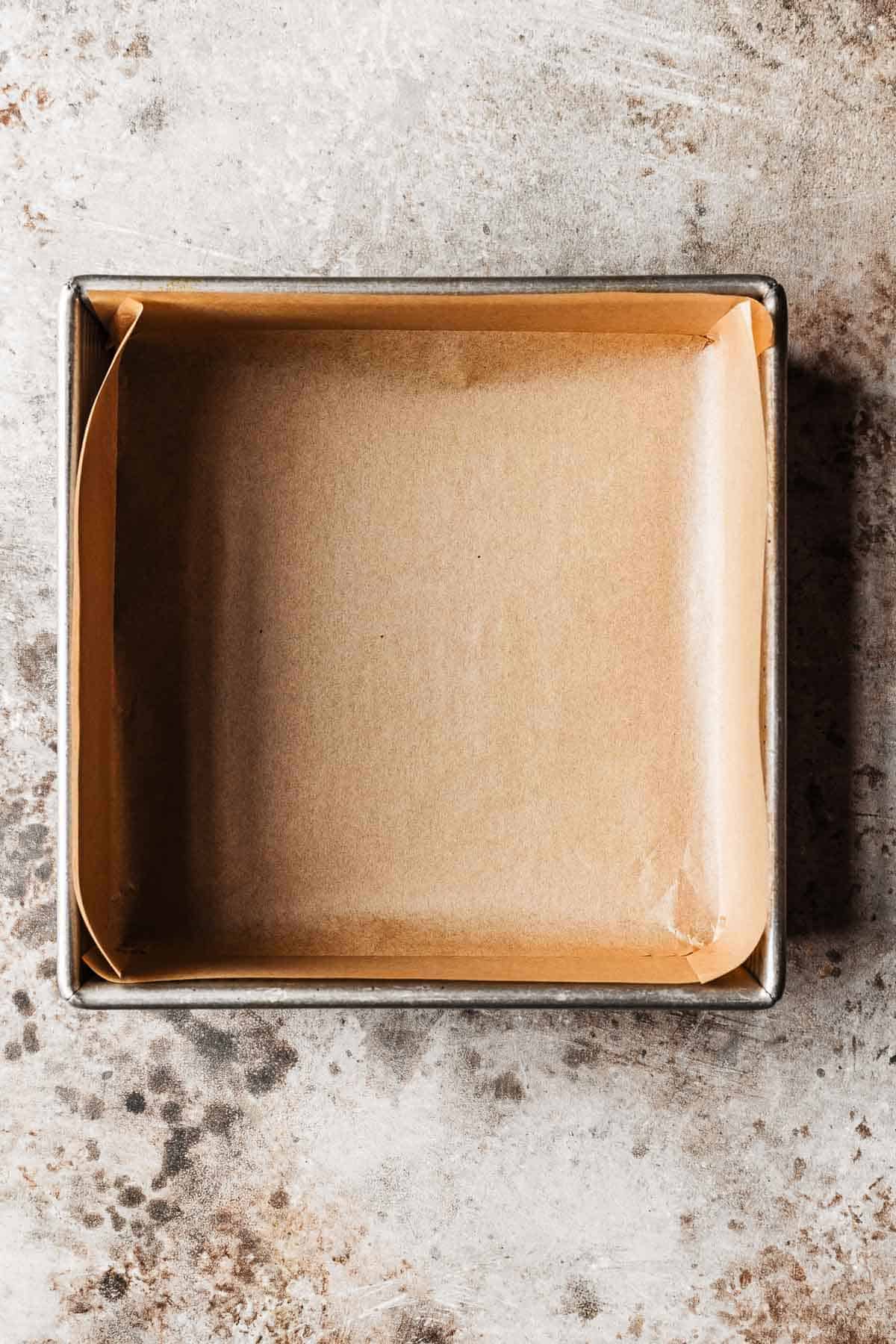 A square metal pan lined with brown parchment paper.