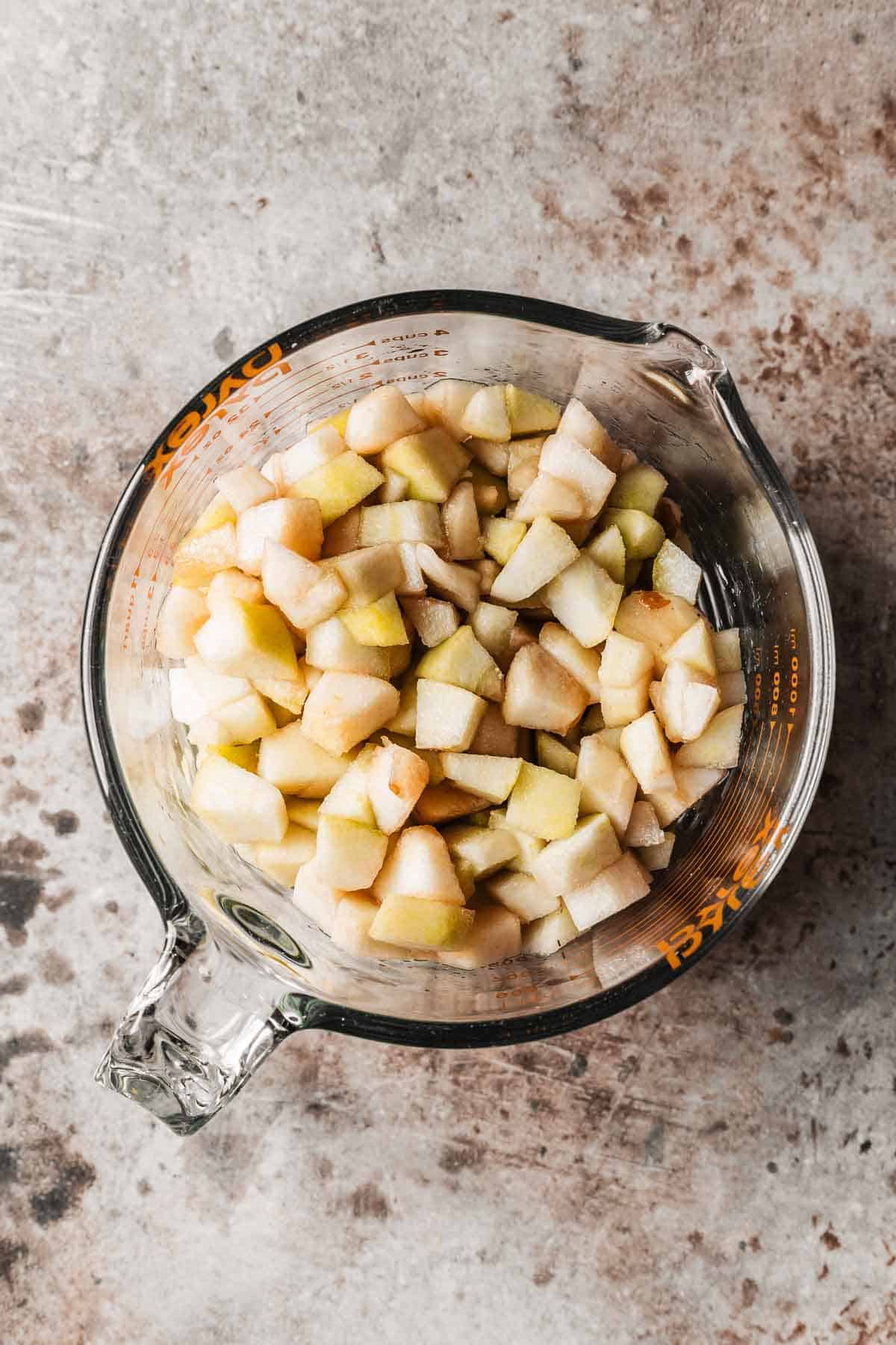 A glass measuring cup with diced pears.