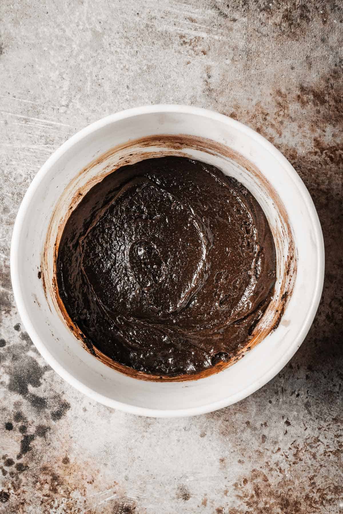 A mixing bowl with wet and dry ingredients fully combined to make a chocolate cake batter.