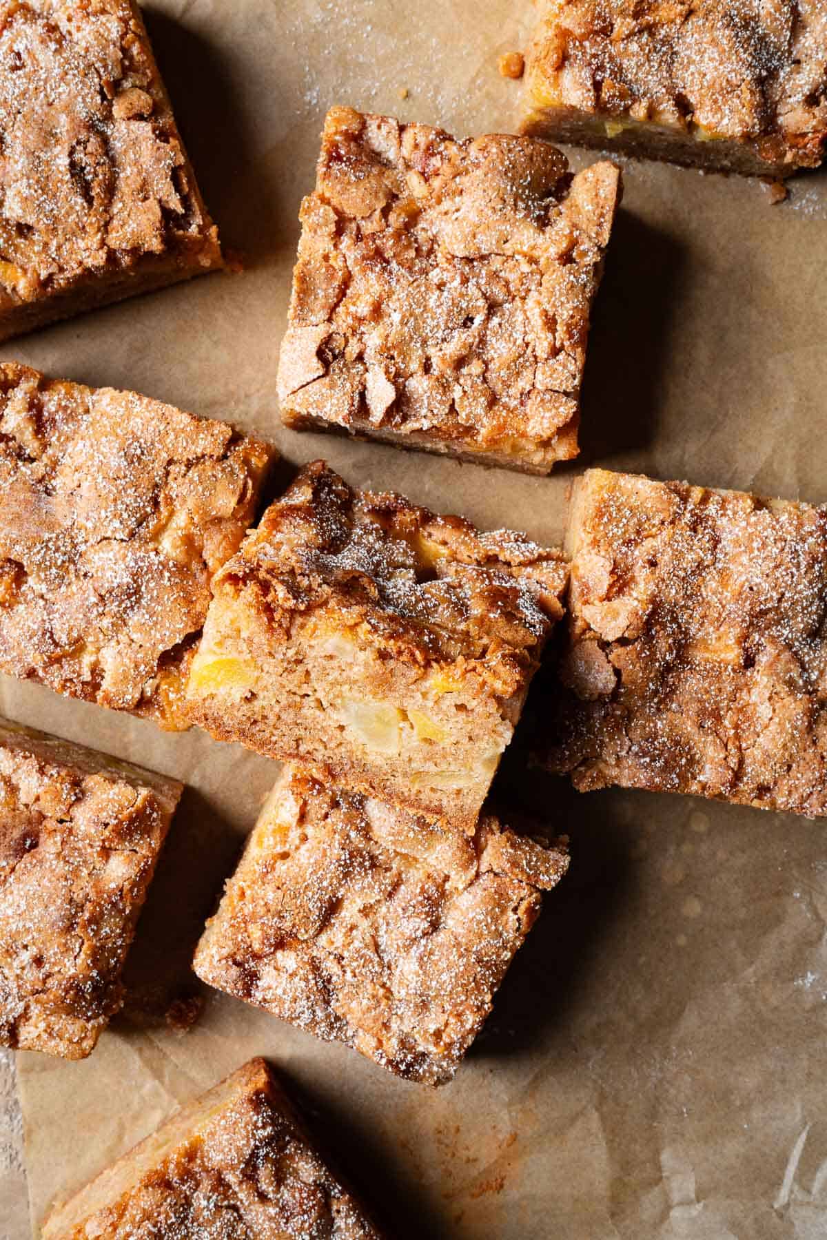 Squares of apple cake on brown parchment.