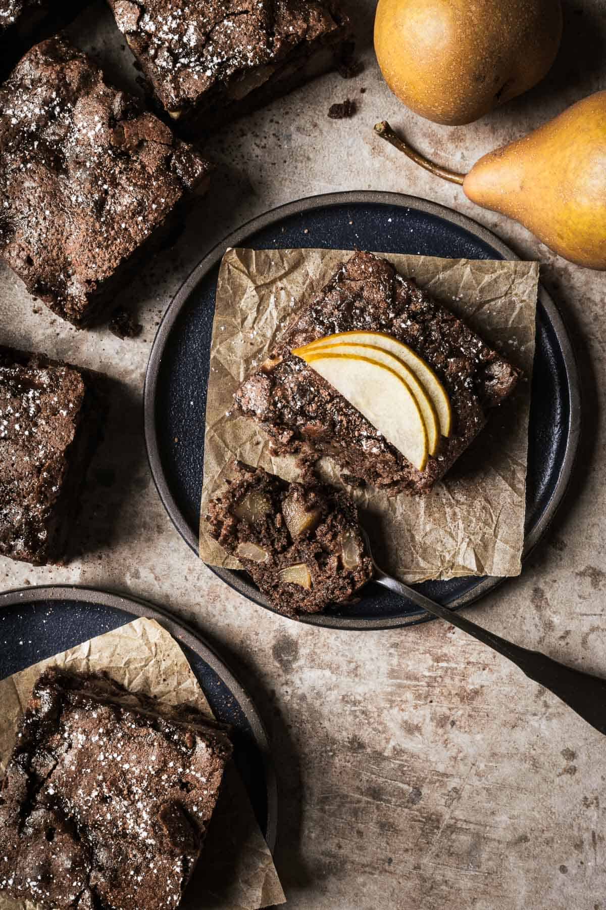 A square of chocolate pear cake with a bite on a fork.