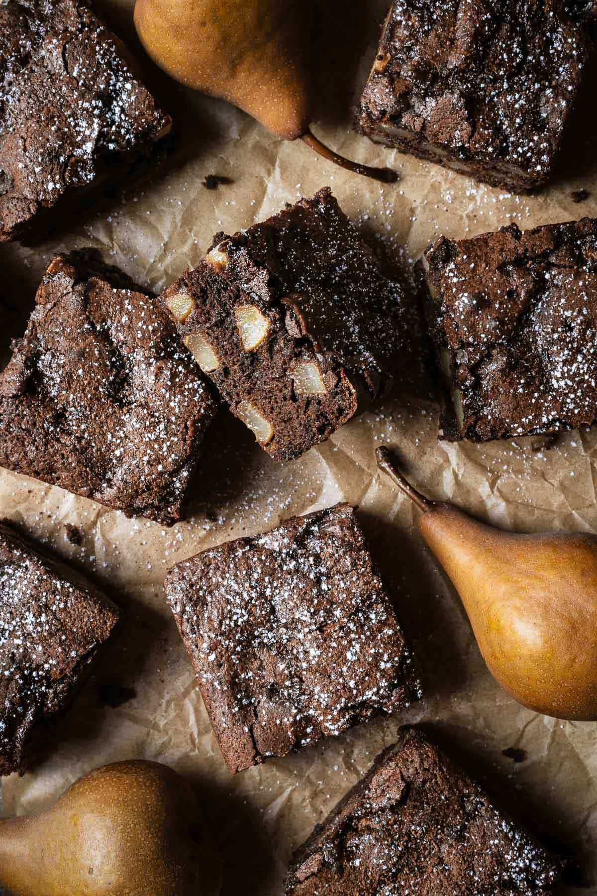 Squares of chocolate pear cake on brown parchment paper.