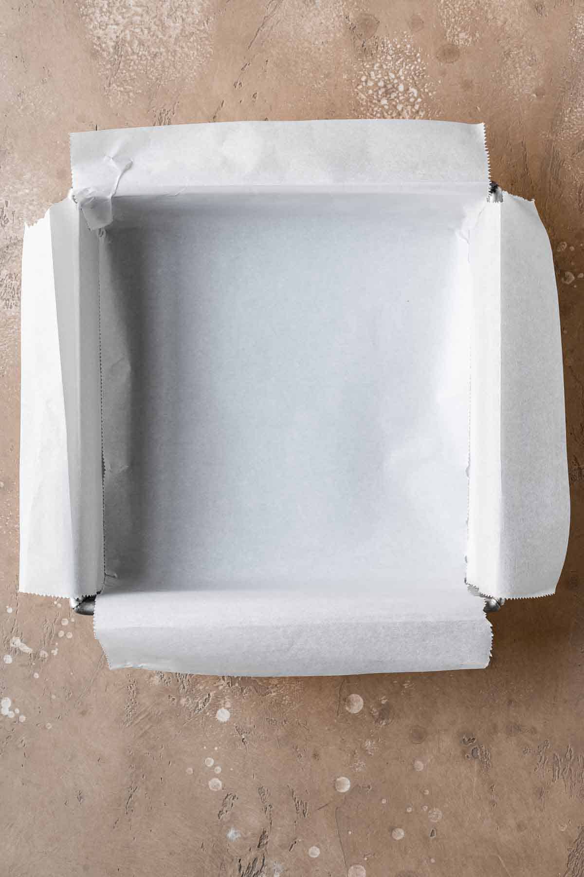 A square metal pan lined with parchment paper.