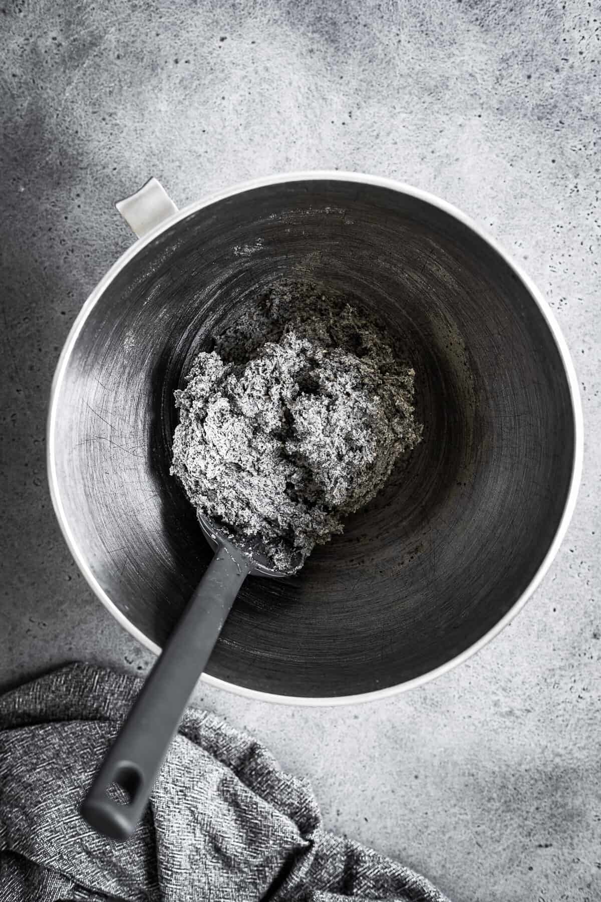 A bowl of cookie dough with dry ingredients added.