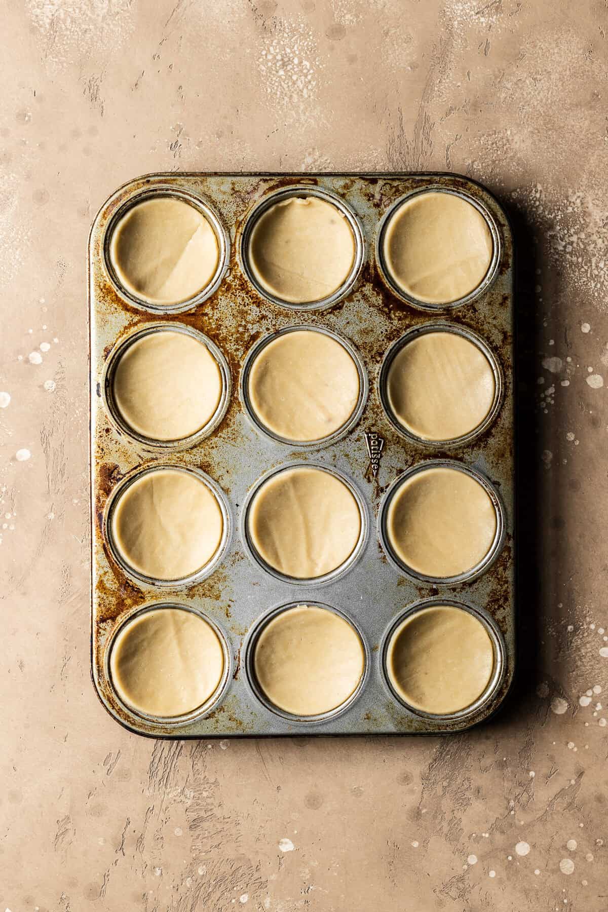 Unbaked dough circles for nutella biscuits in a muffin pan.