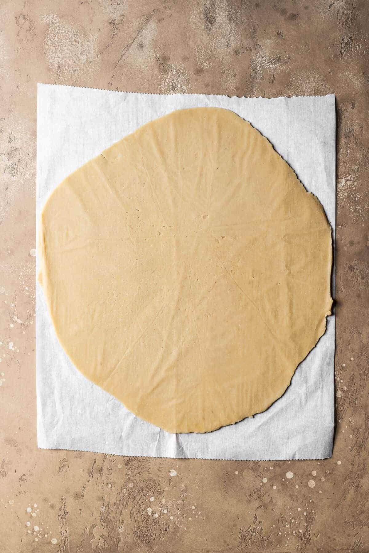 Rolled dough for nutella biscuits on white parchment paper.