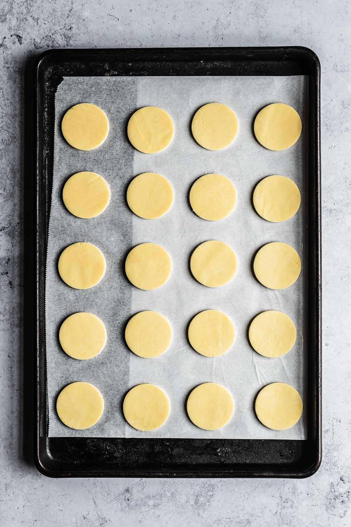 Circles of cookie dough on a parchment lined baking sheet.