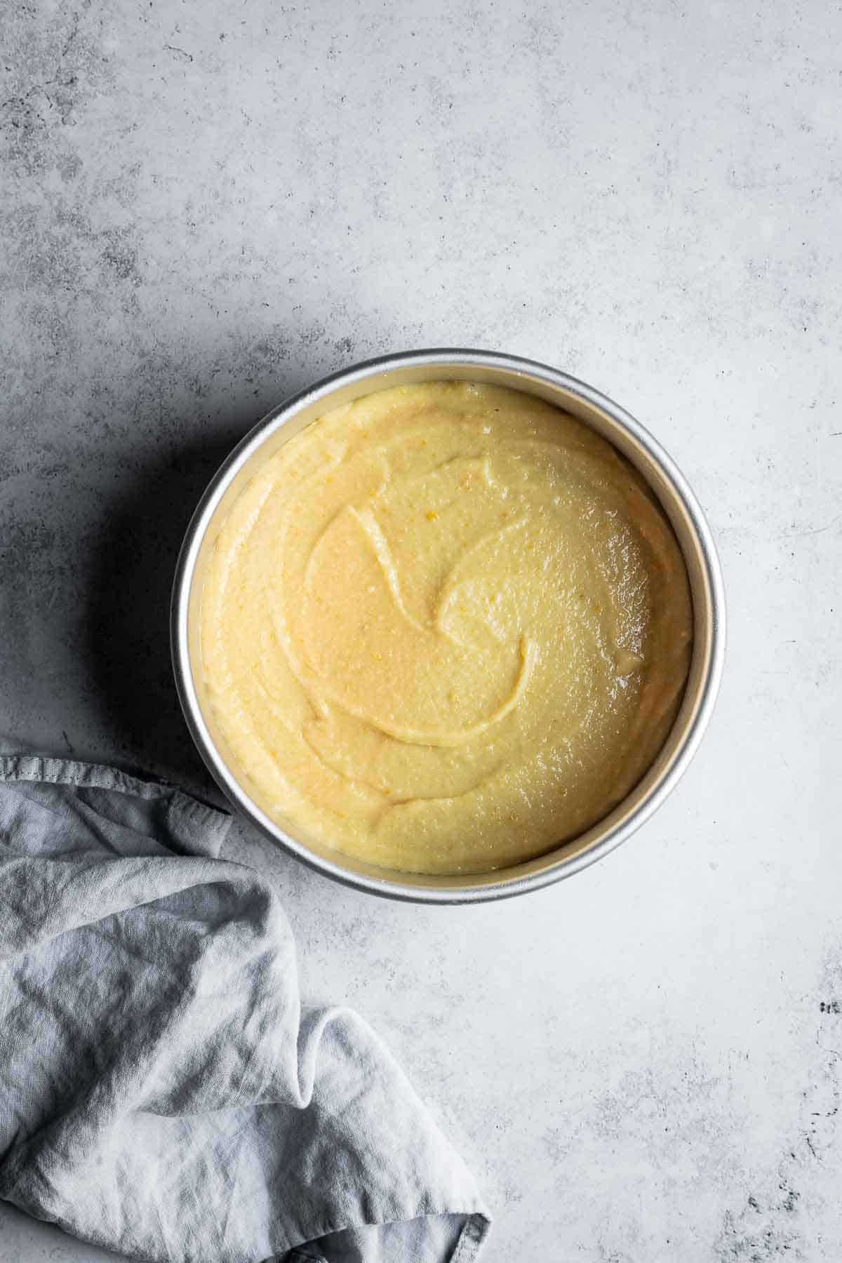 A round cake pan filled with lemon yellow cake batter.