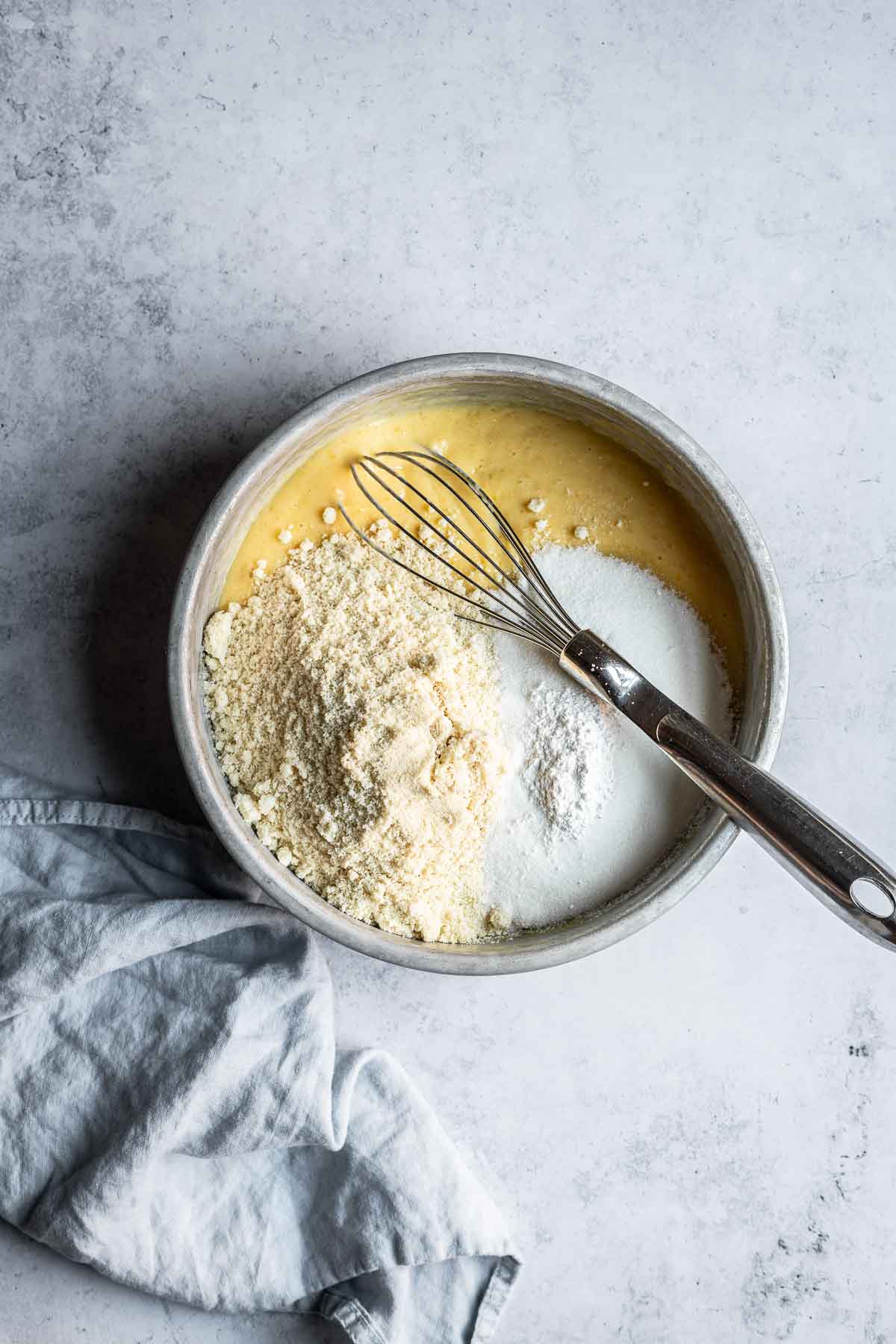 A mixing bowl of wet and dry ingredients for a cake batter.