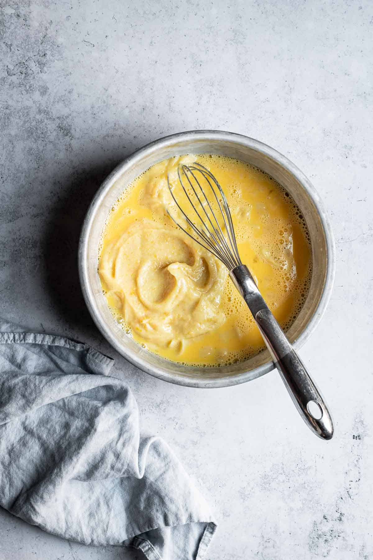 A mixing bowl with eggs and lemon puree inside.