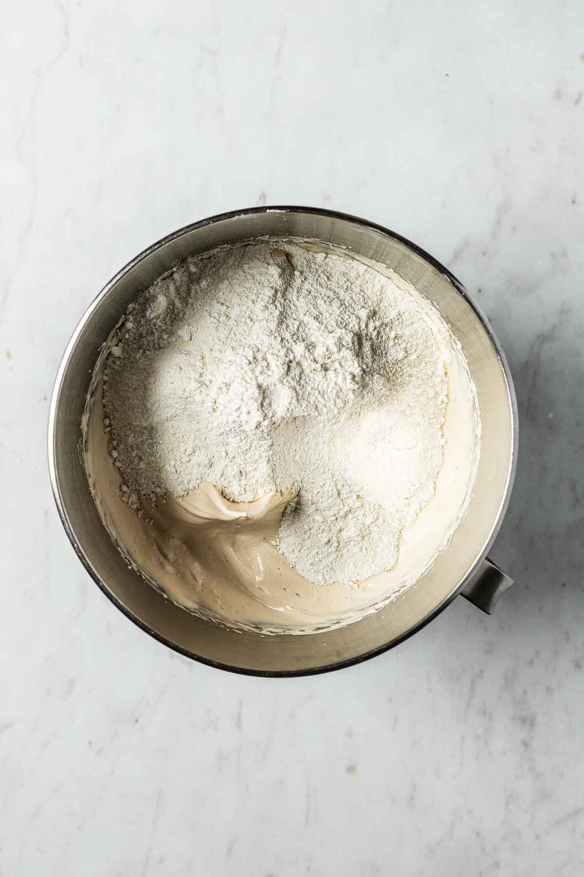 Almond flour and powdered sugar in a mixing bowl on top of brown sugar meringue.