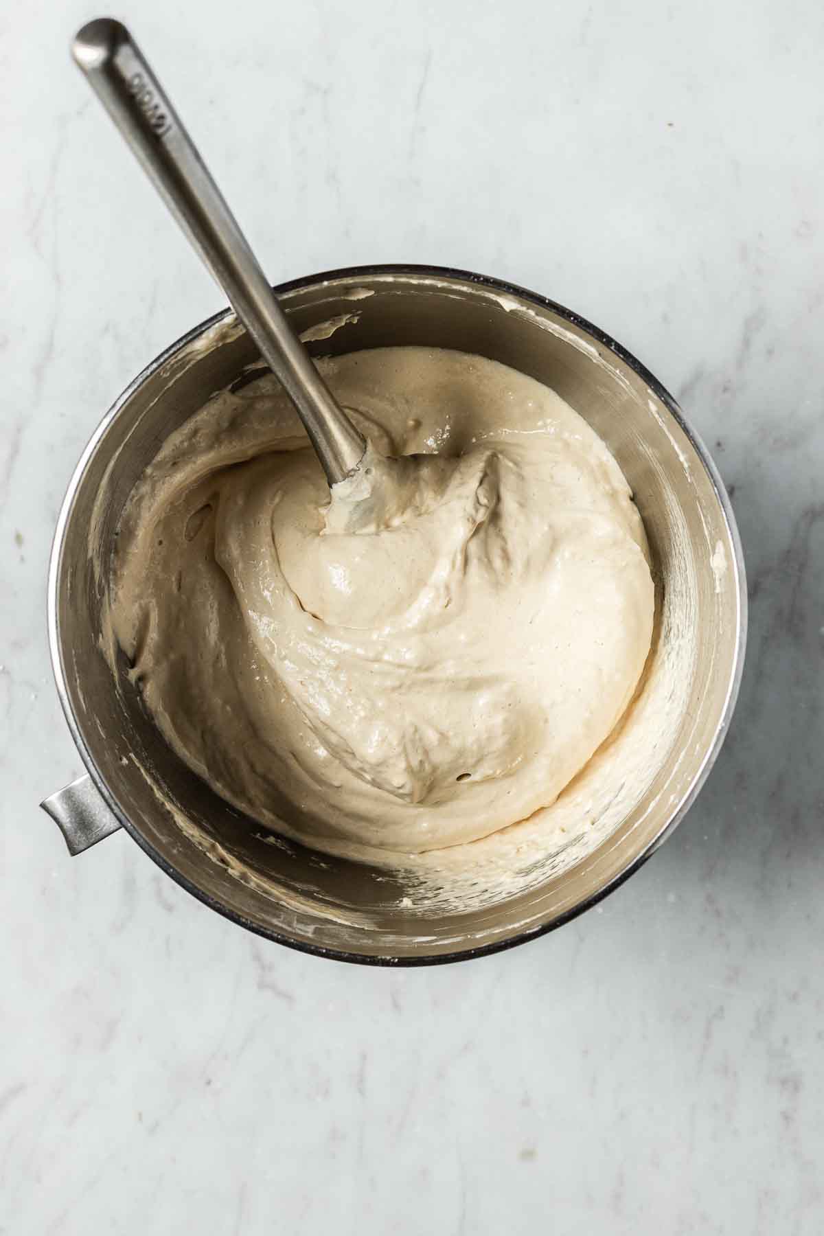 A mixing bowl of almond flour and powdered sugar being folded into meringue.