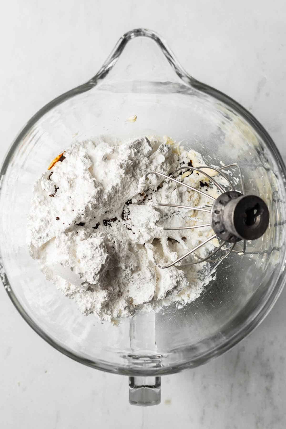 Butter, powdered sugar, espresso powder, vanilla and salt in a glass mixing bowl for frosting.
