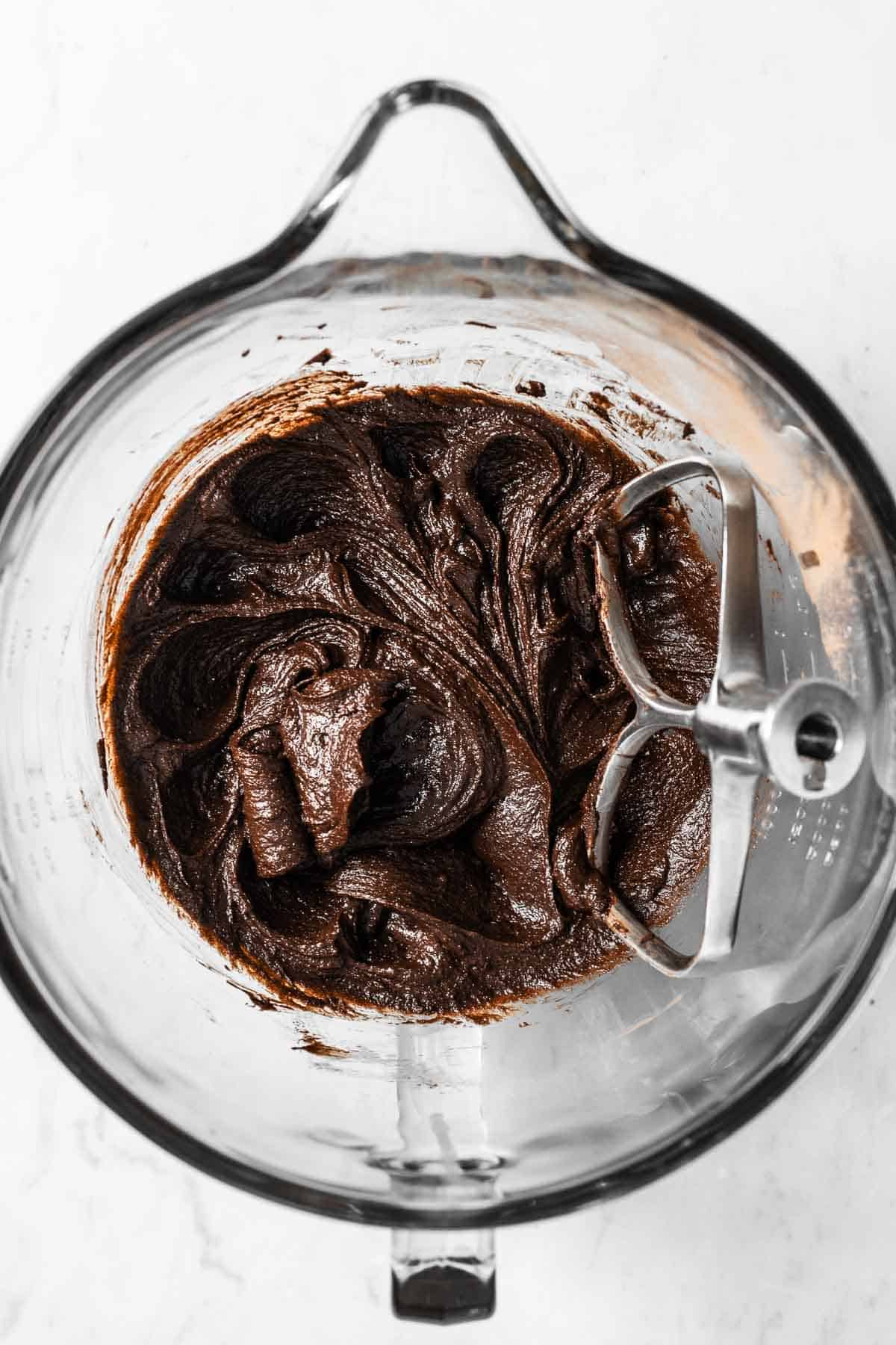 An egg fully mixed into the wet ingredients for chocolate cookie dough.