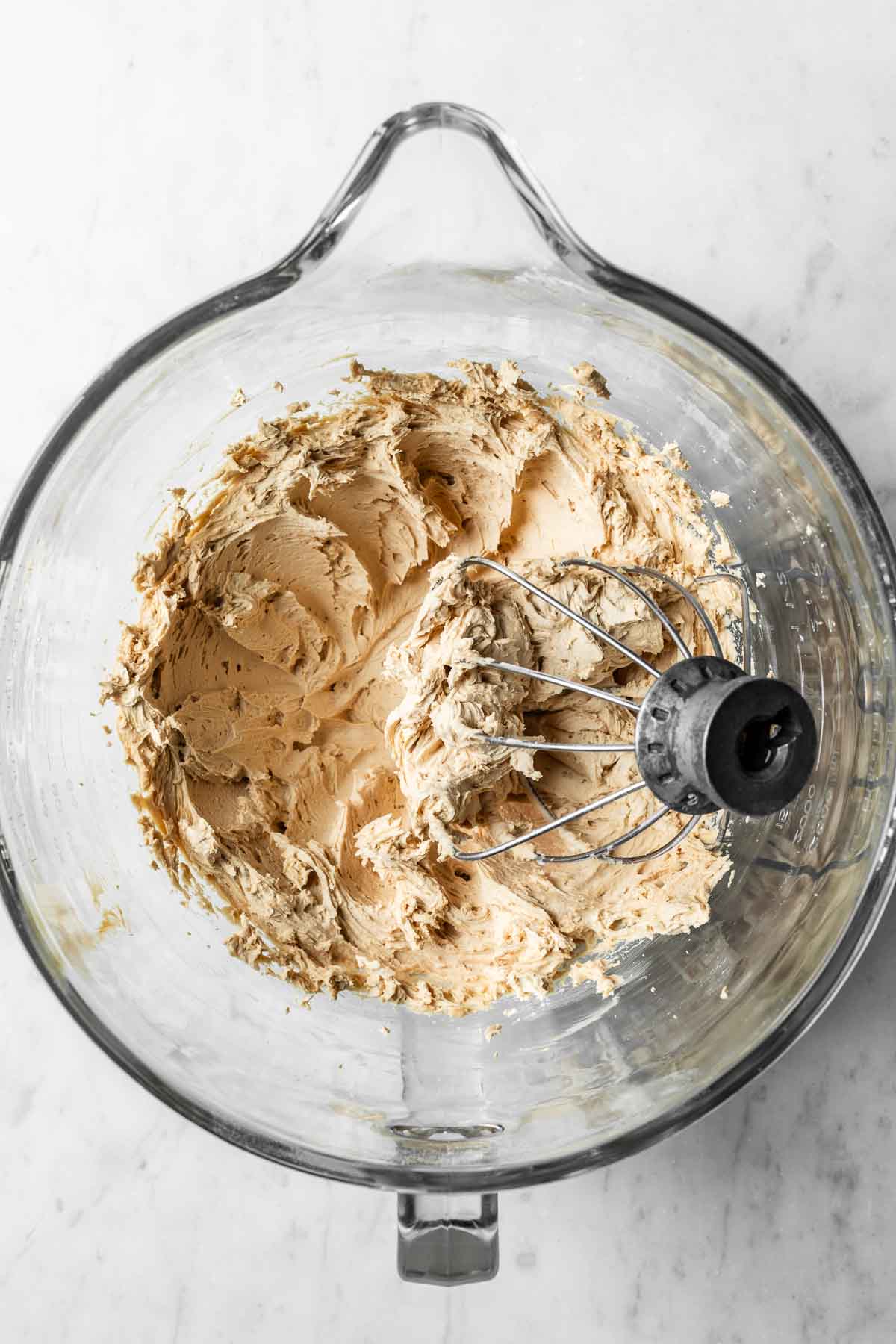 Whipped coffee buttercream frosting in a glass mixing bowl.