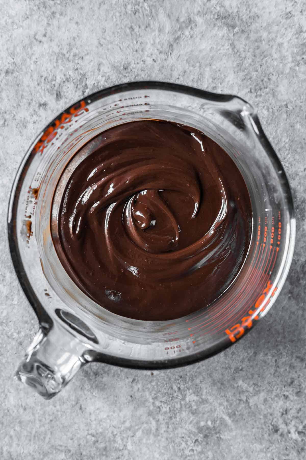Melted chocolate ganache in a large glass container.