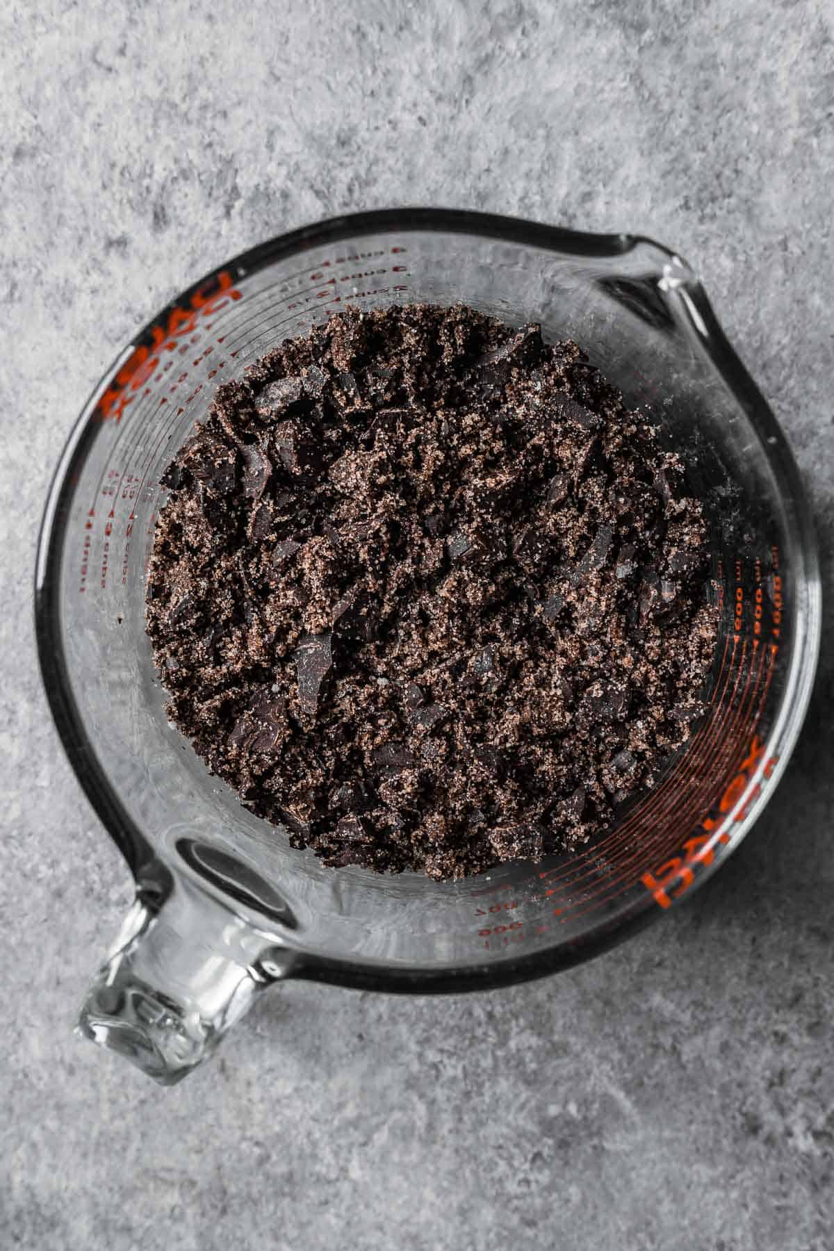 Chopped chocolate, sugar, vanilla and salt well mixed together in a glass mixing container.