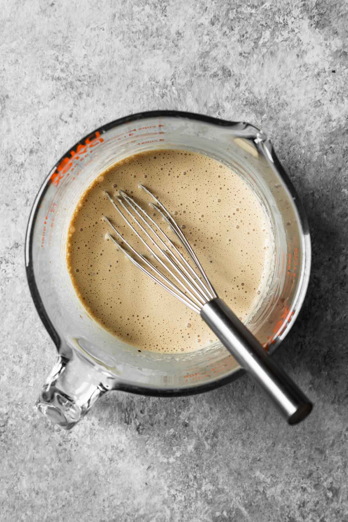 Cream, sugar and instant espresso powder whisked together in a glass measuring container.