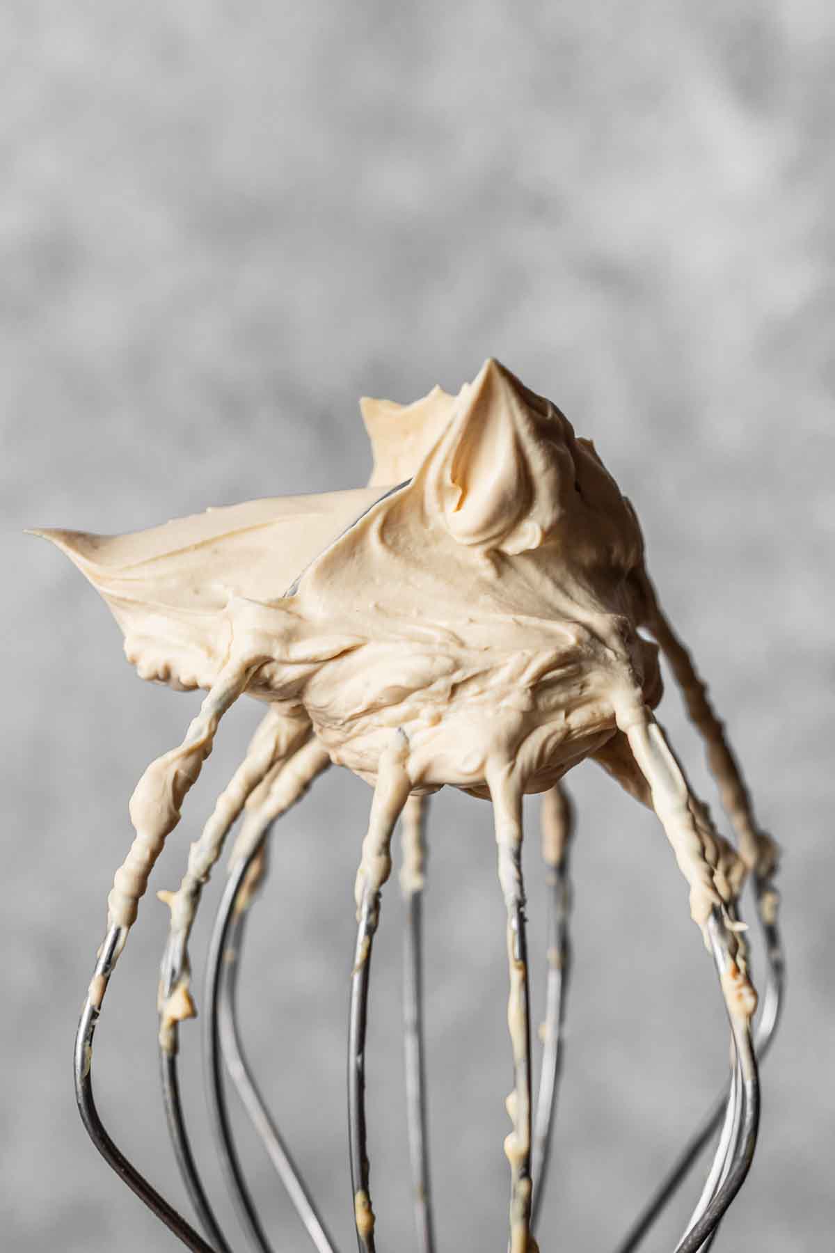 Stiff peaks of whipped coffee mascarpone cream on the end of a whisk.