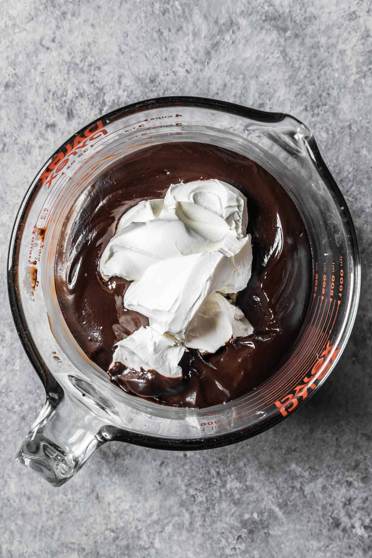 Melted chocolate ganache and mascarpone cheese in a large glass container.