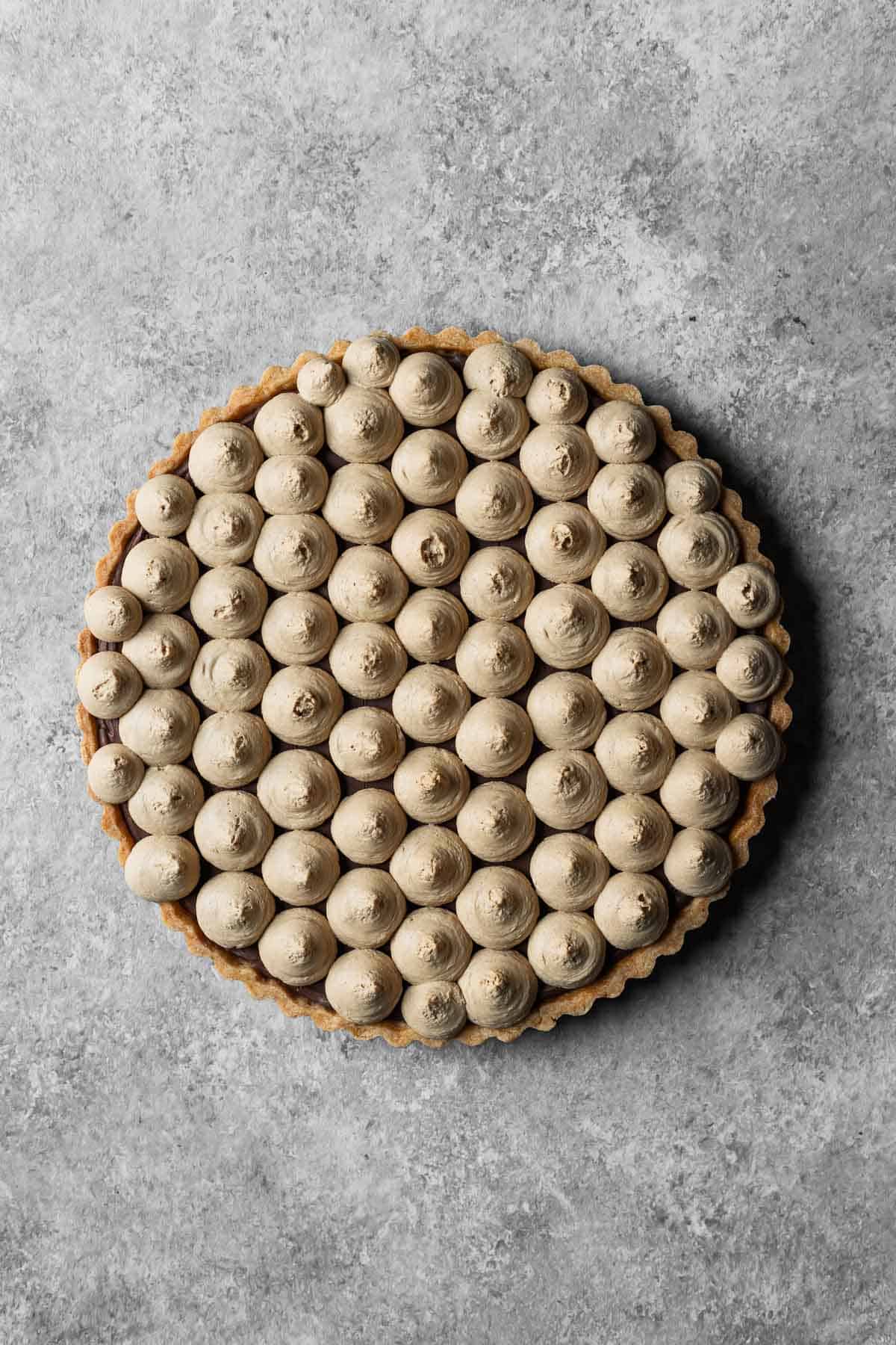 A chocolate mascarpone ganache tart covered in piped circles of coffee mascarpone.