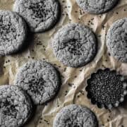 Baked grey cookies with black sesame seeds sprinkled on top.