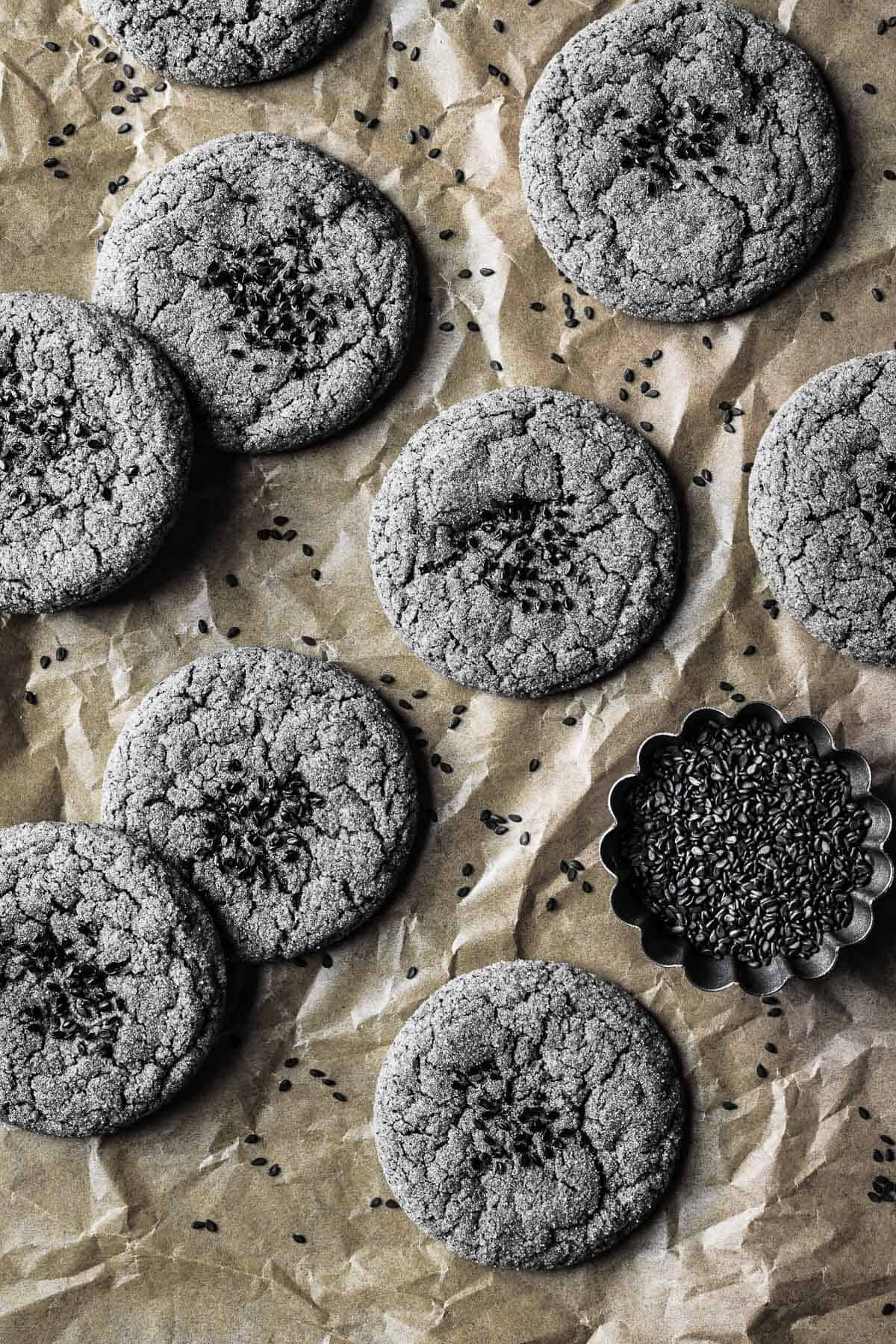 Baked grey cookies with black sesame seeds sprinkled on top.