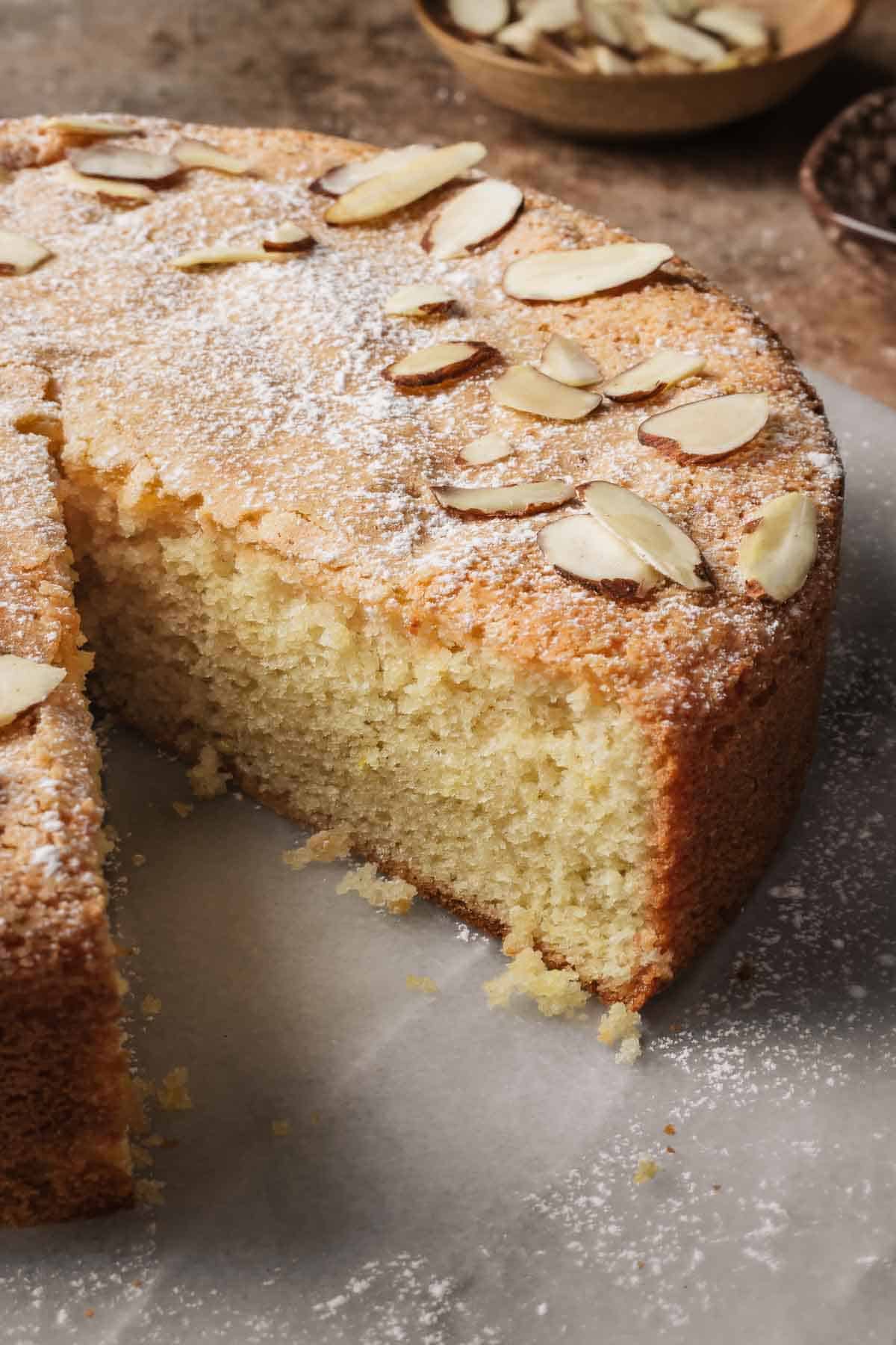 An almond cake with a slice removed to show the interior crumb.