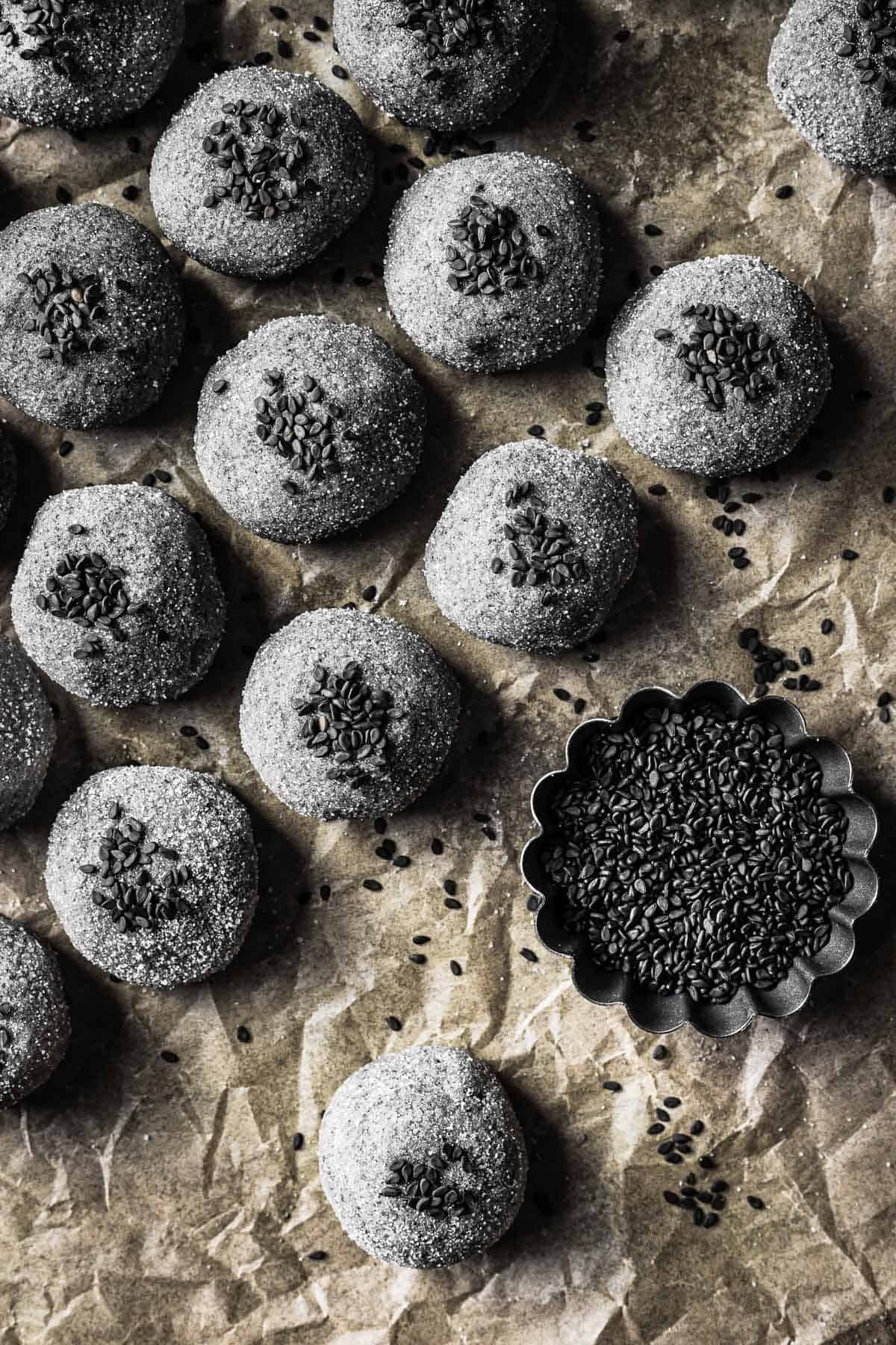 Scoops of grey cookie dough rolled in sugar and sprinkled with black sesame seeds.