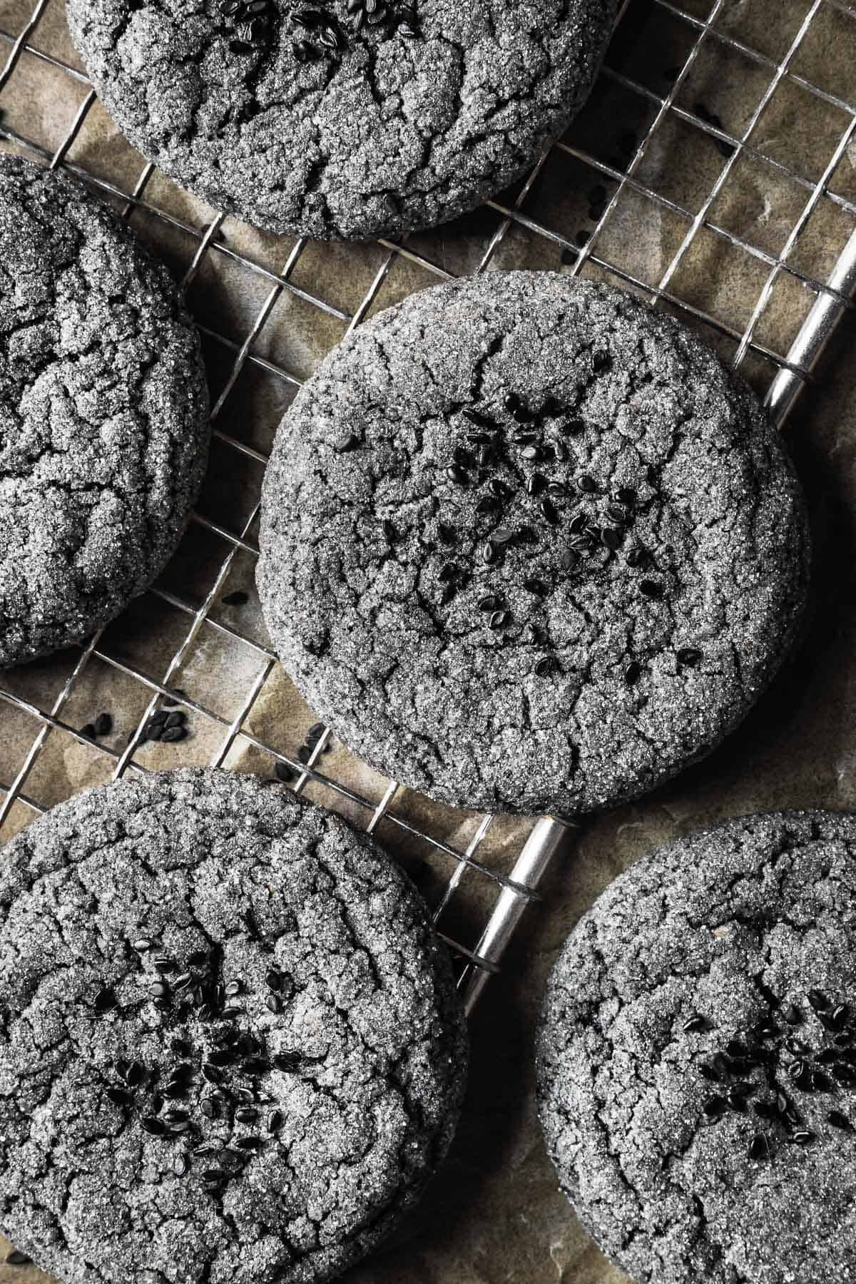 A close up of black sesame cookies on a metal cooling rack.
