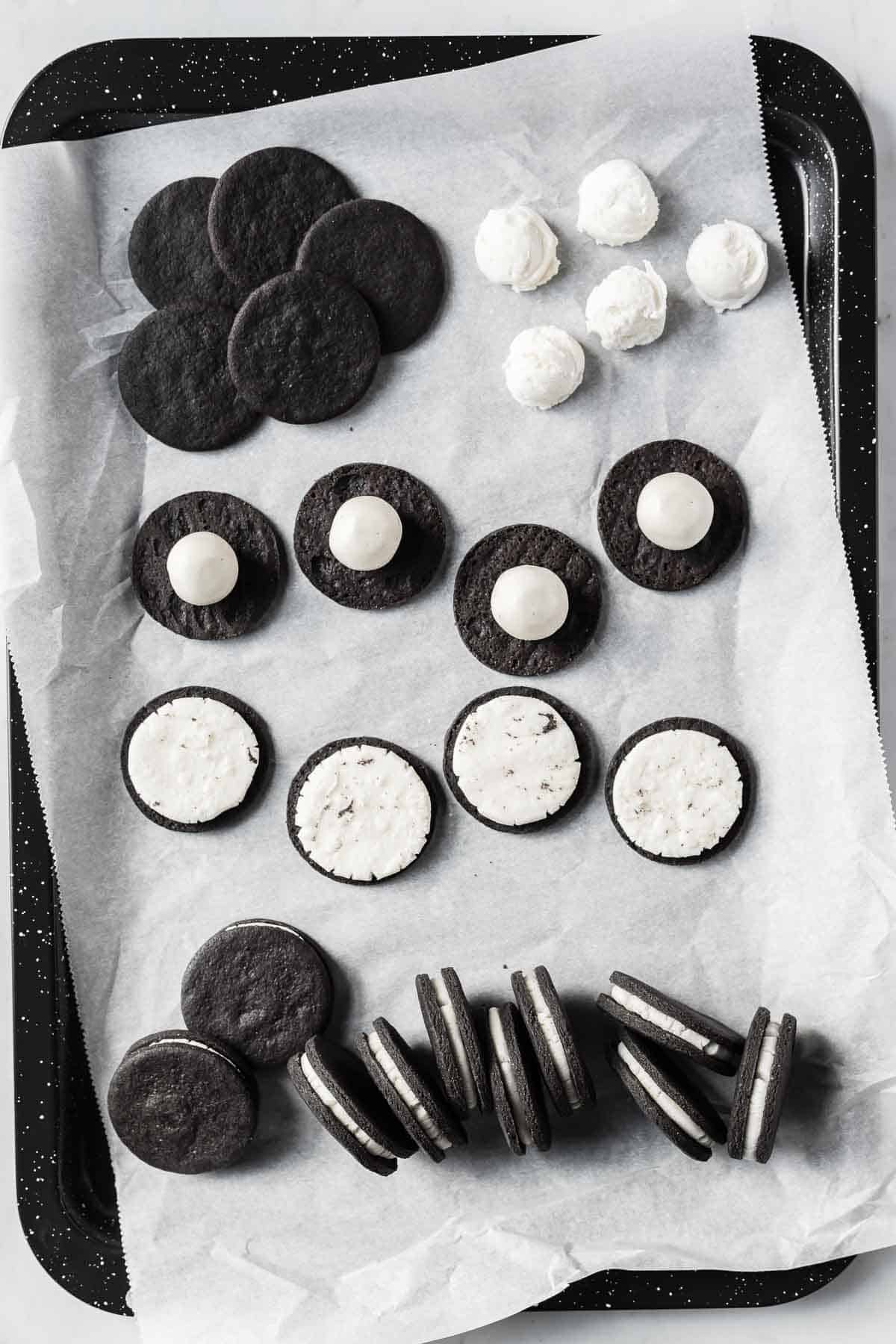 Oreo cookie filling in different stages of preparation: rolled into balls, resting on cookie halves, pressed into flat discs, sandwiched between cookies.