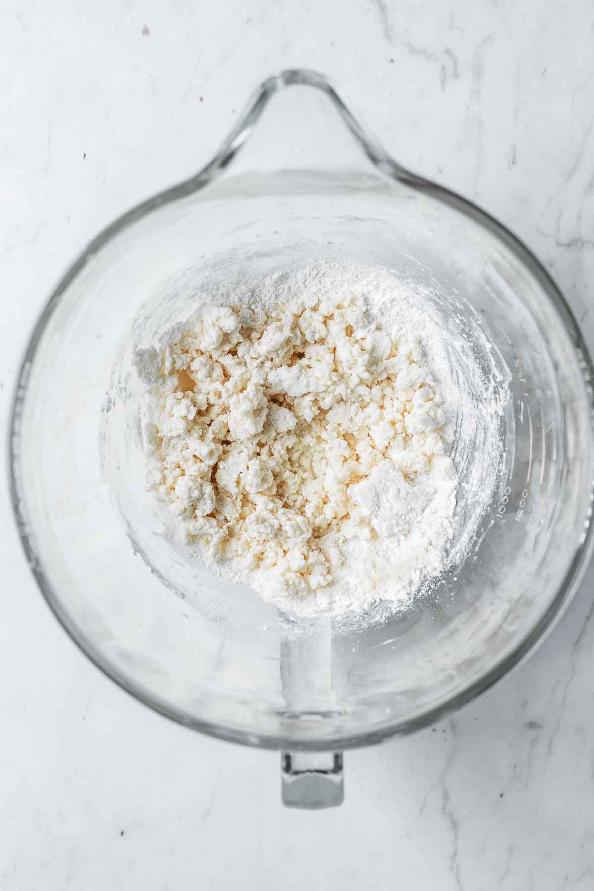 Dry ingredients partially added to wet ingredients in a glass mixing bowl.