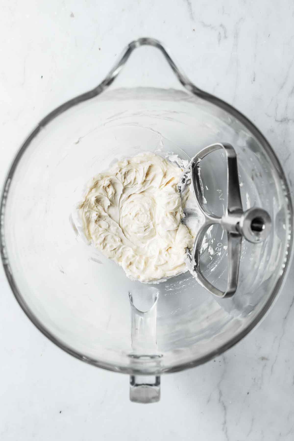 Fully combined palm shortening, vanilla and corn syrup in a glass mixing bowl with a metal paddle attachment.