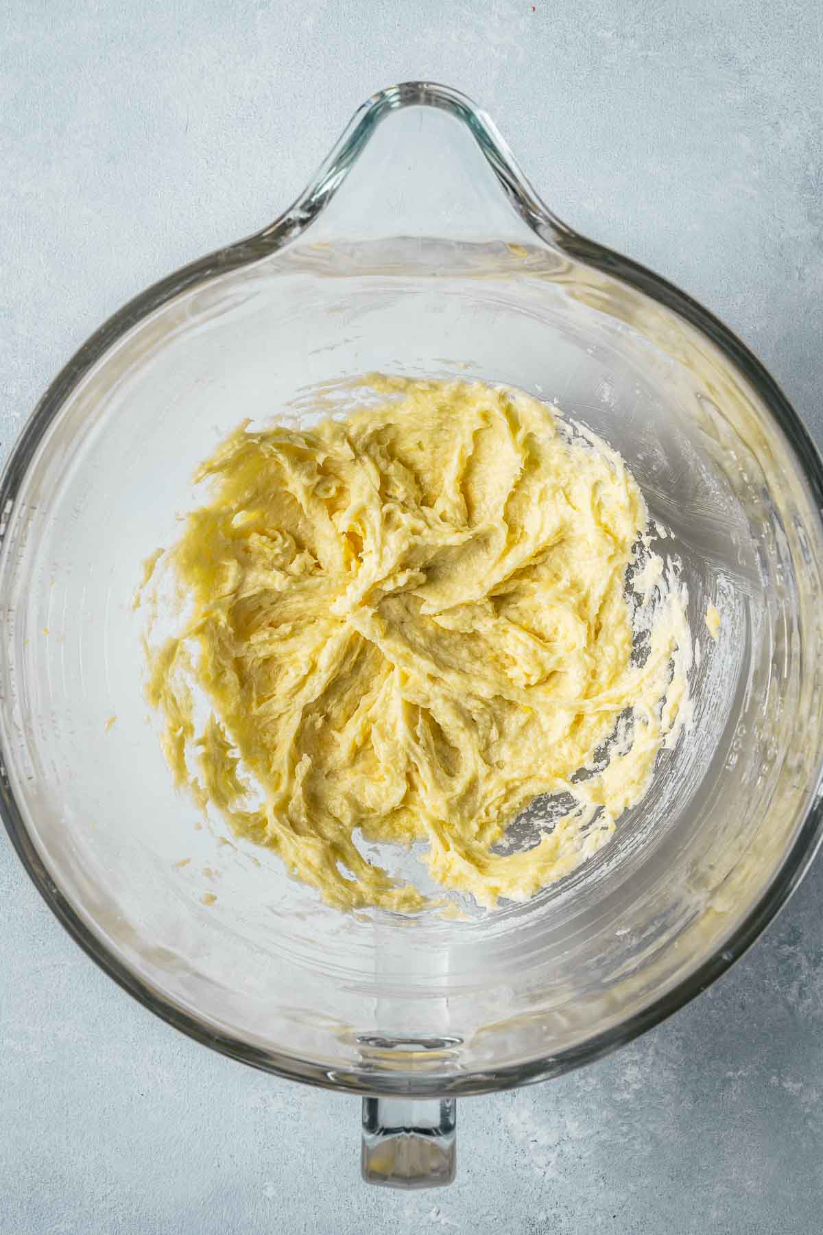 Wet ingredients mixed with butter and sugar in a clear glass bowl.