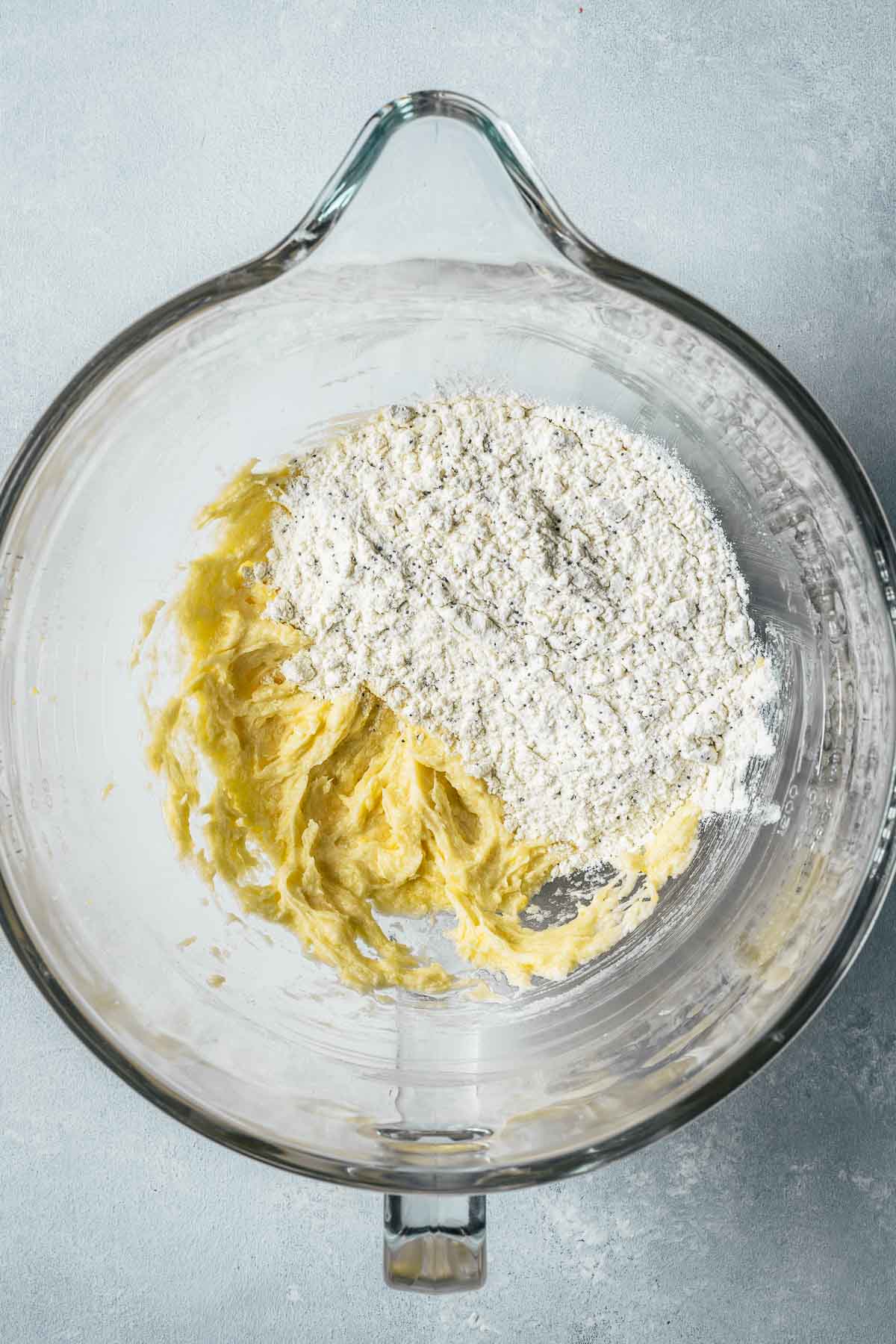 Dry ingredients added to wet batter in a clear glass mixing bowl.
