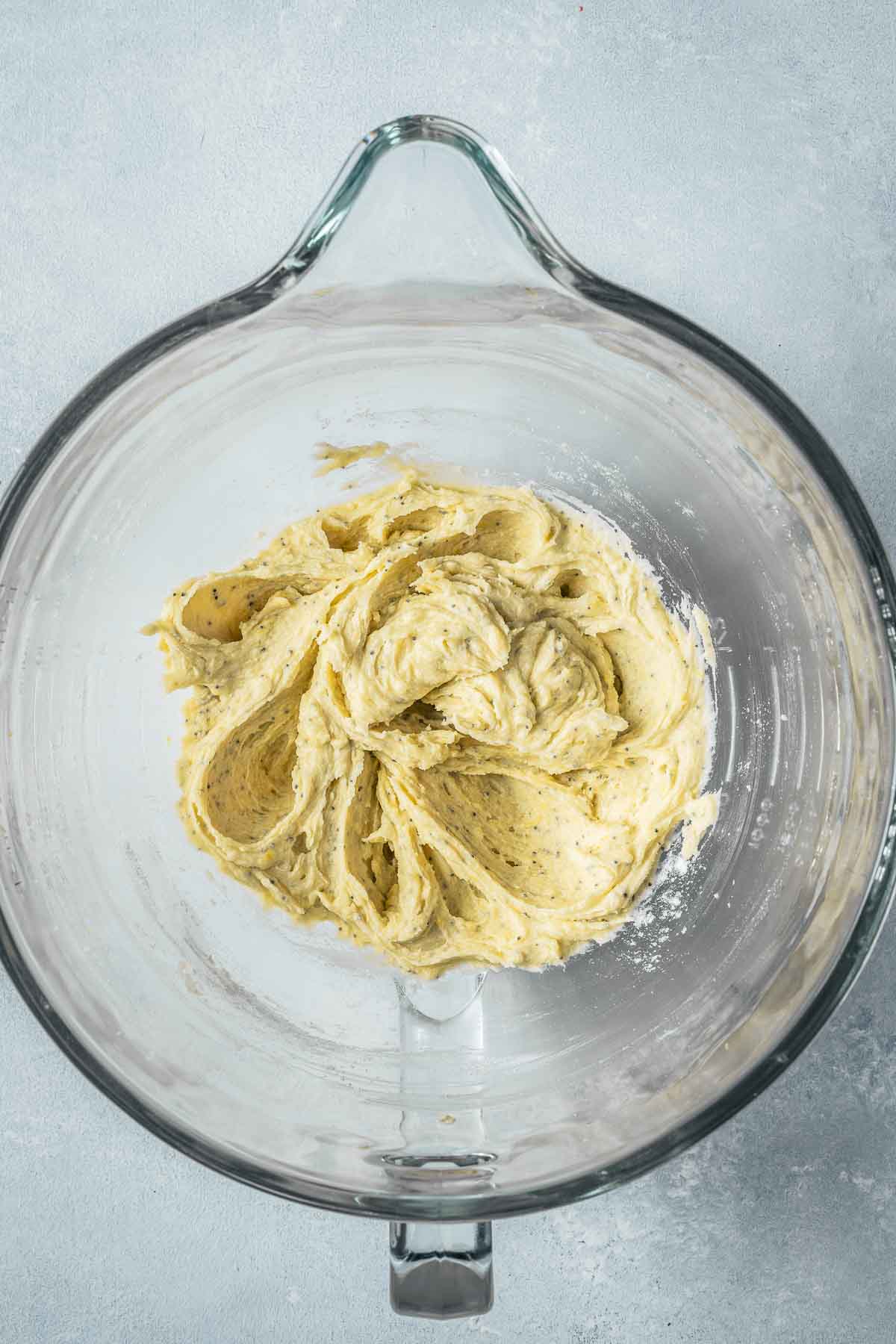 Batter with the first addition of flour incorporated in a clear glass mixing bowl.