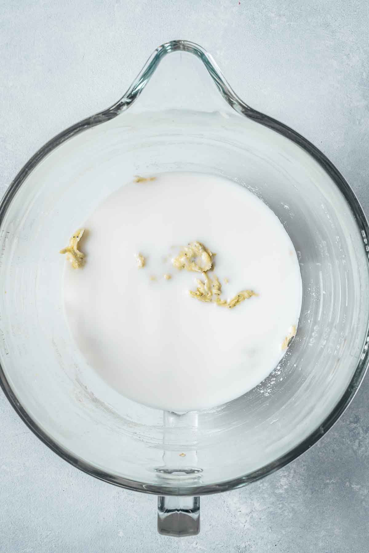 Milk added to muffin batter in a clear glass mixing bowl.