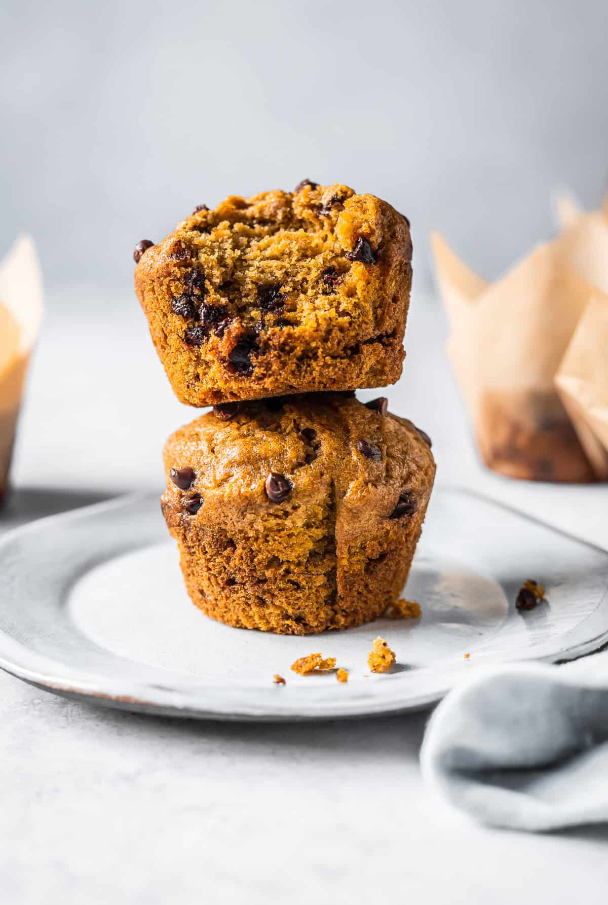 Two muffins stacked on a white ceramic plate.