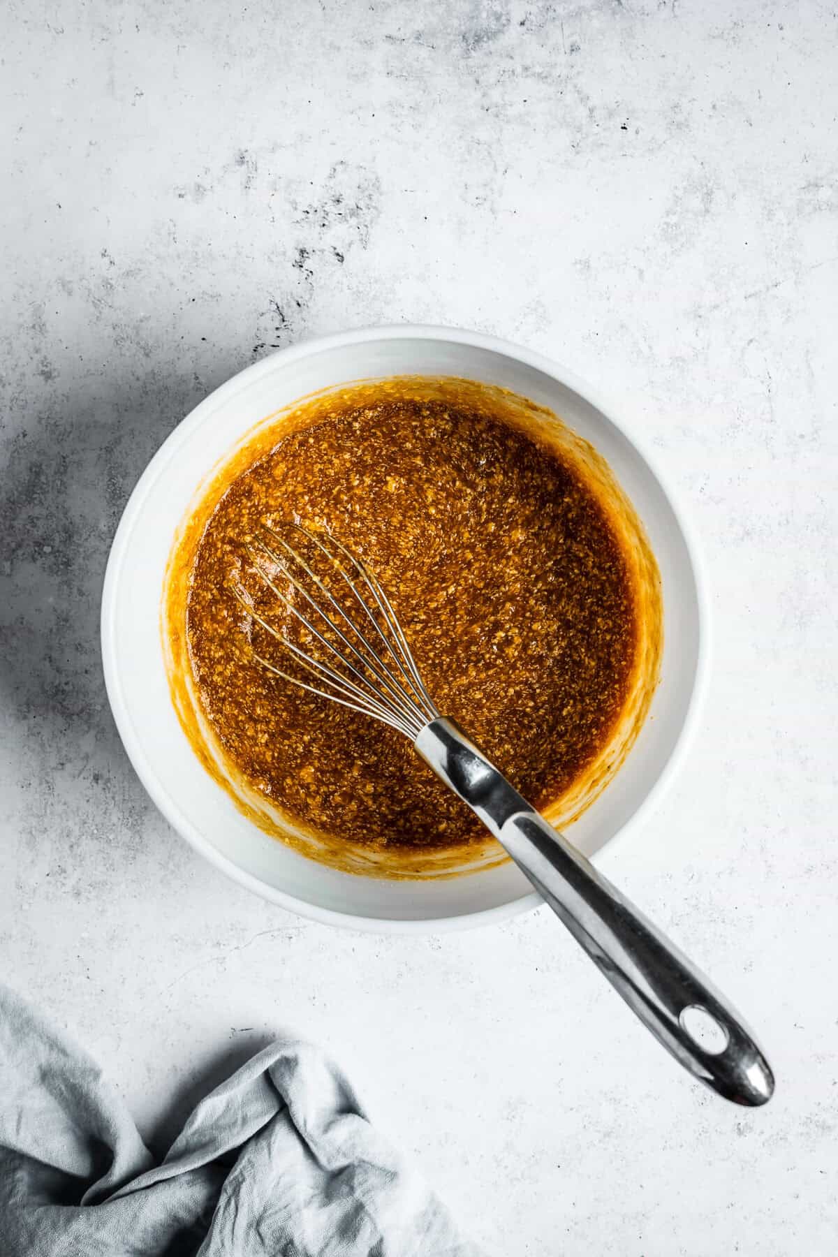 Sugar whisked into batter in a white glass mixing bowl.