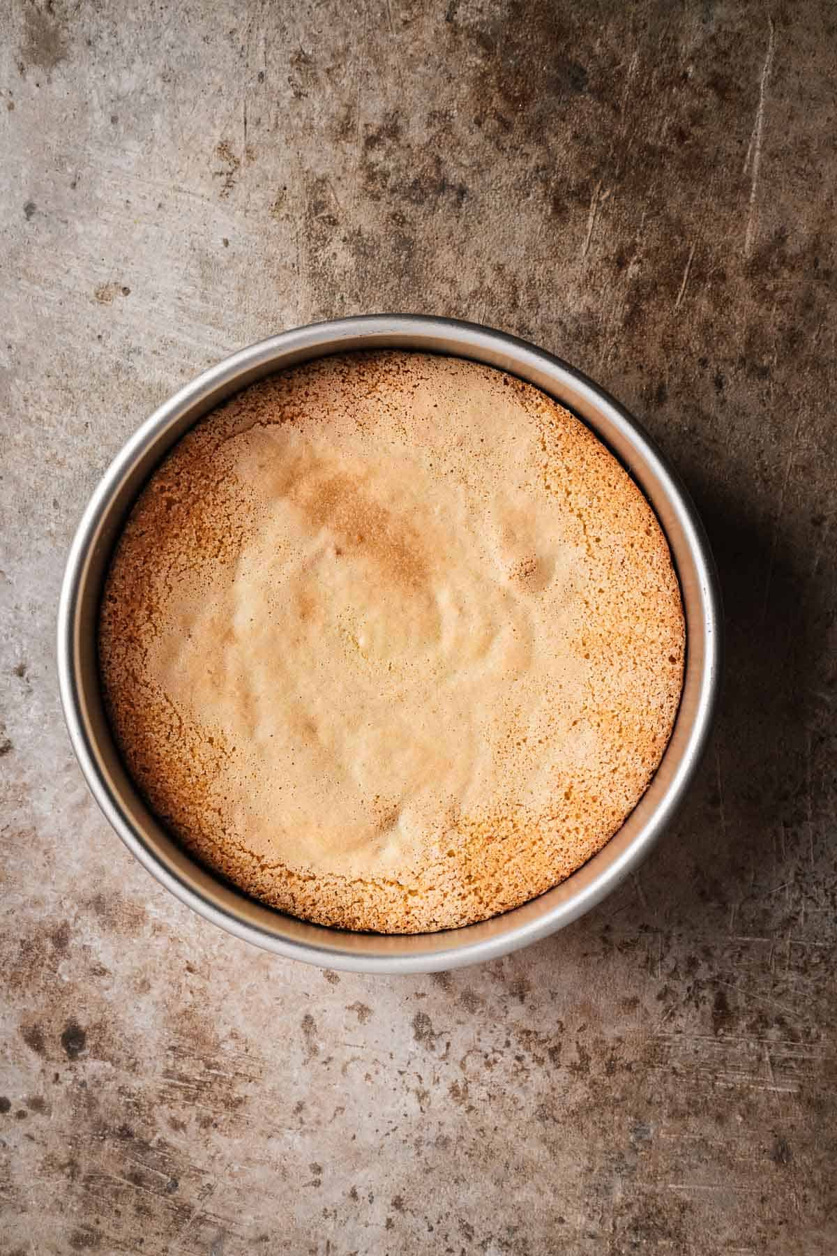 A baked cake in an 8 inch round metal pan.