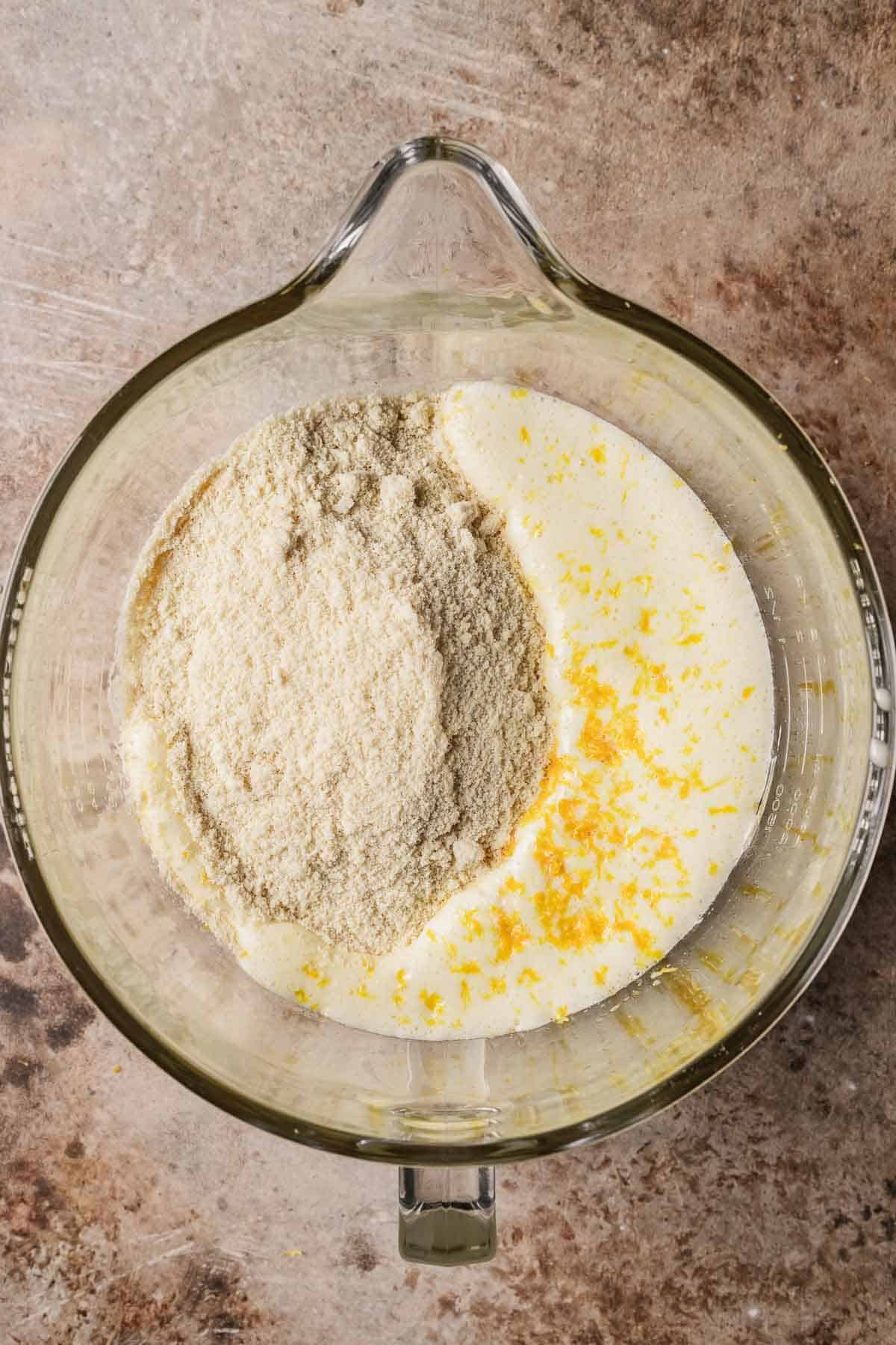 Dry ingredients added to wet ingredients in a glass mixing bowl.