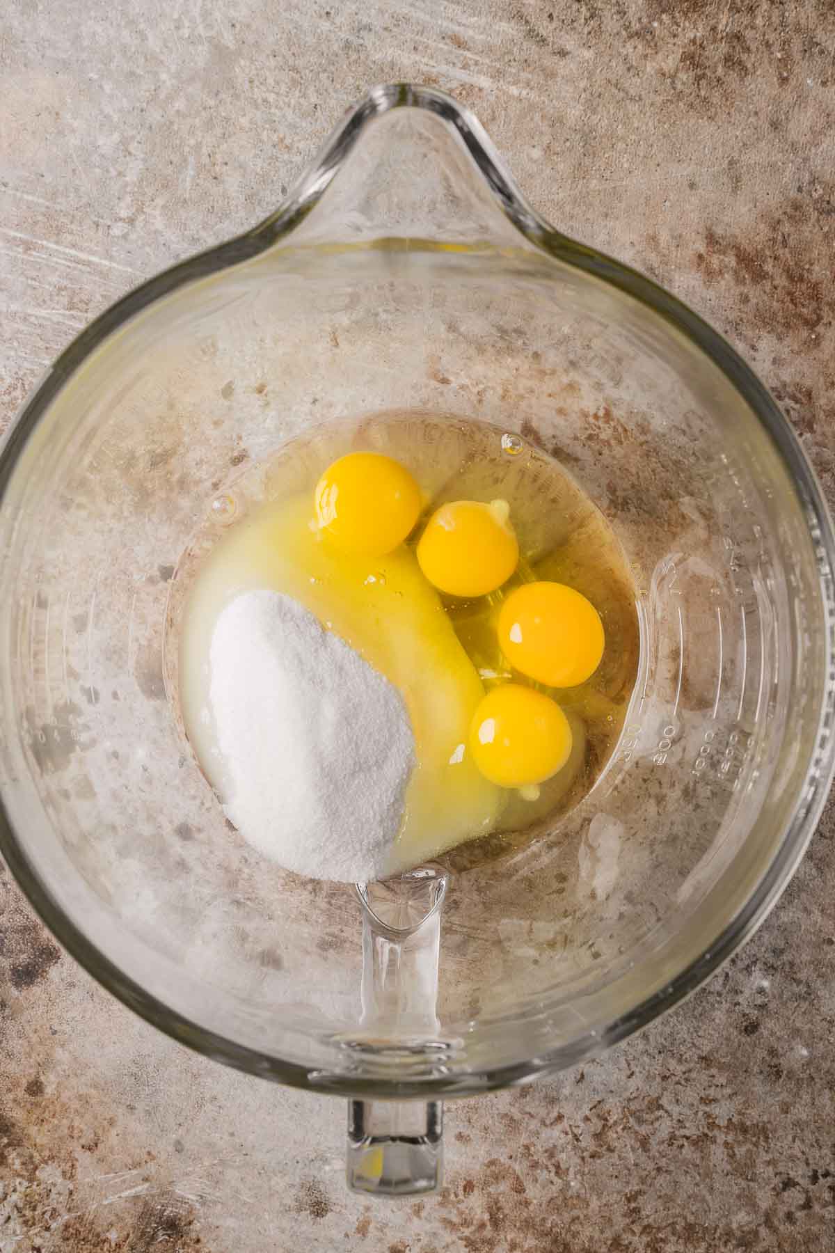 Eggs and granulated sugar in a glass mixing bowl.